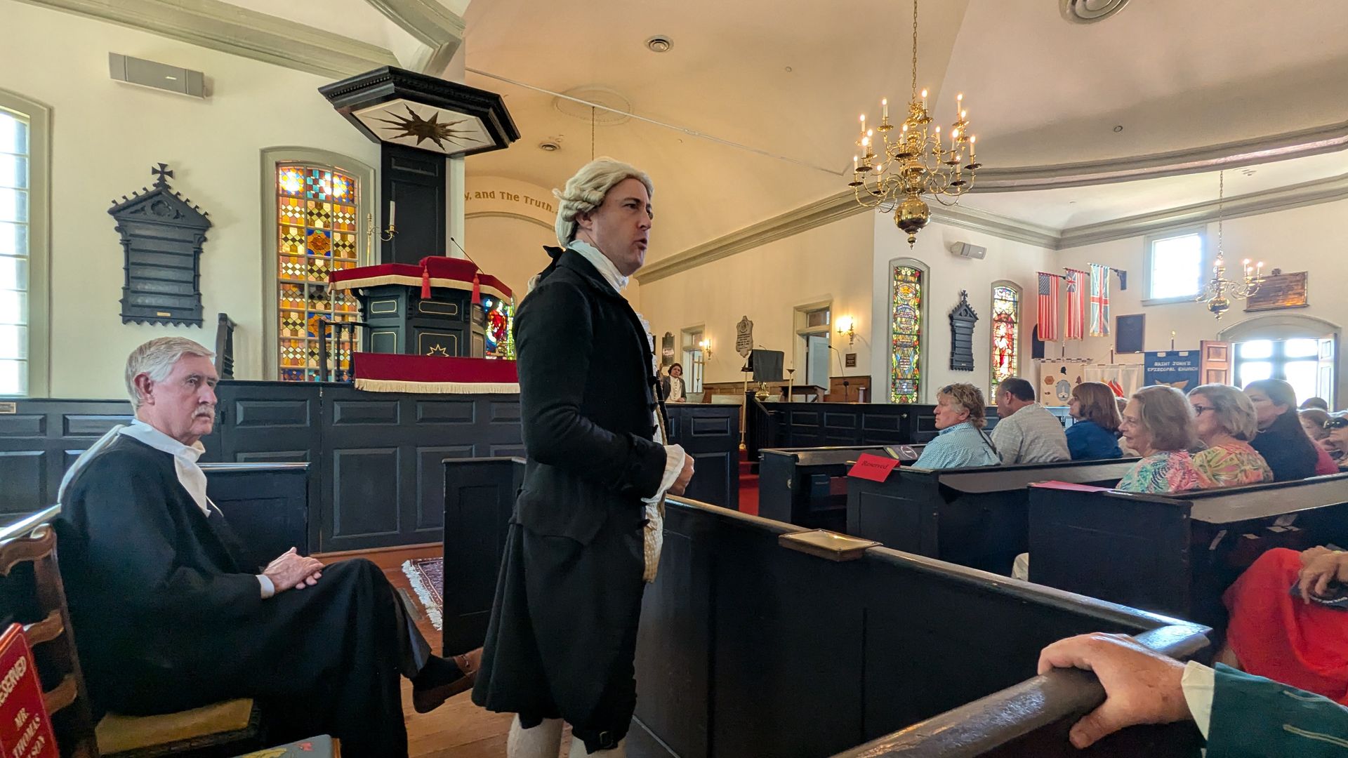 a man in a wig speaking in an old church 