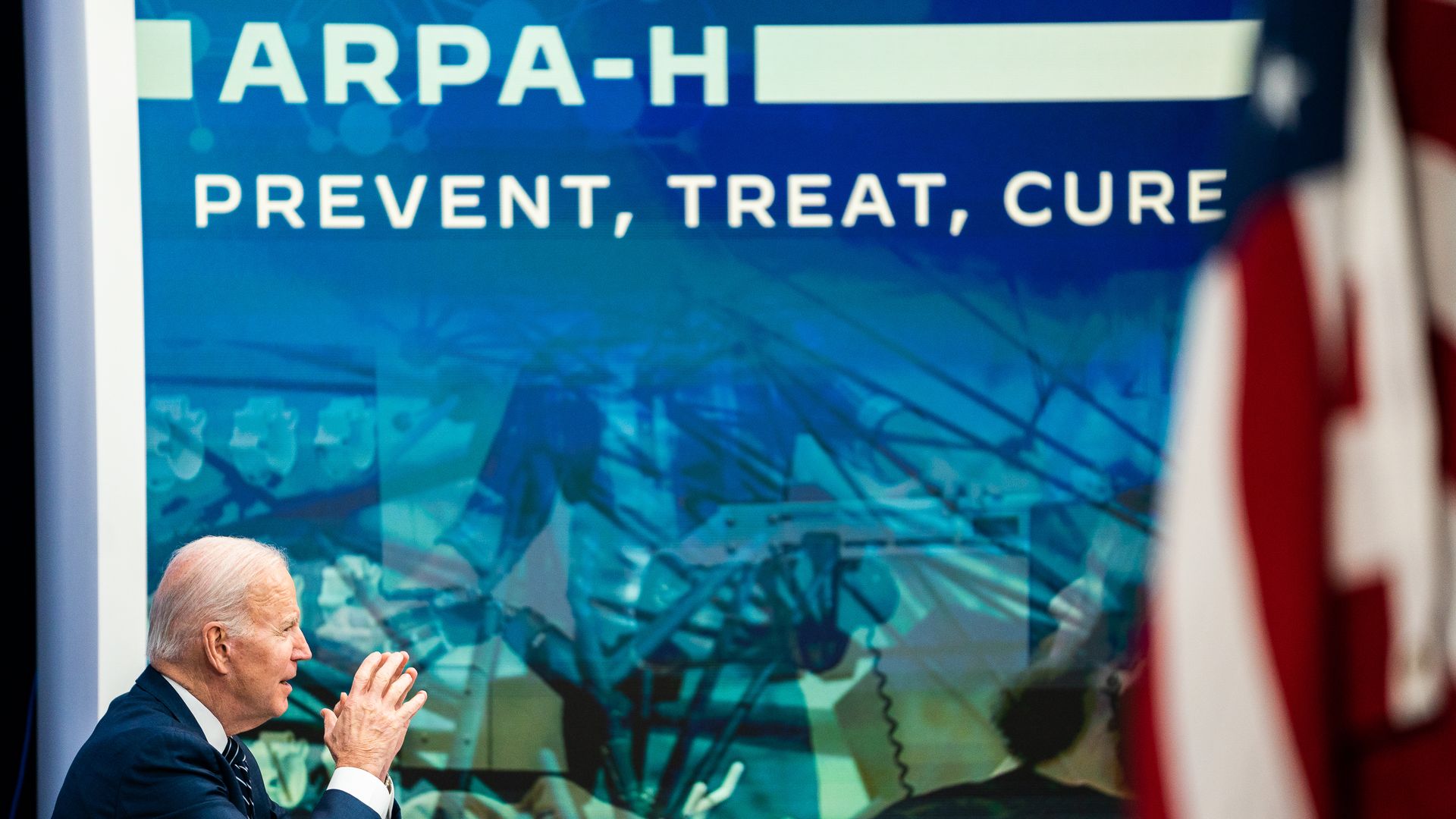 A white man with white hair sits in profile to the left in front of a blue screen that says ARPA-H: Prevent, Treat, Cure.