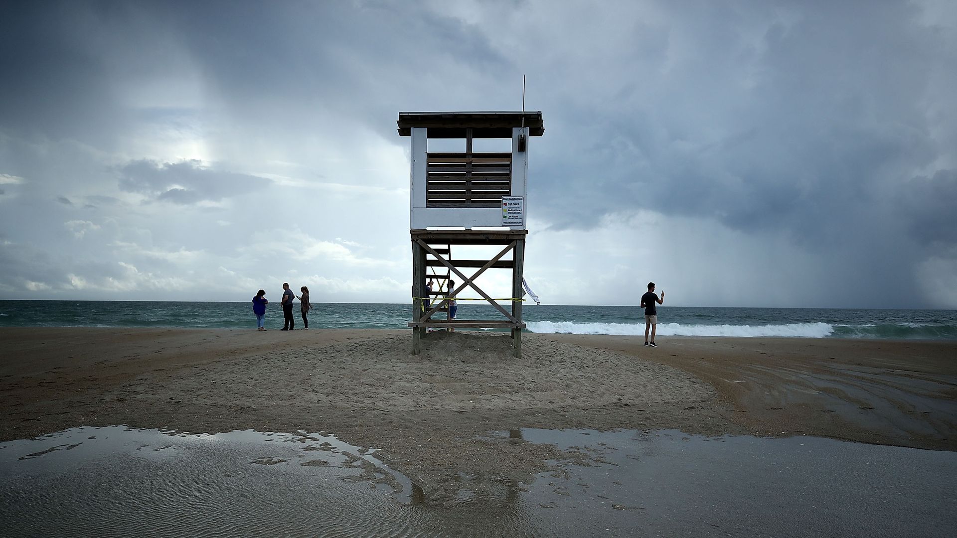 People stand near a lifeguard stand as Hurricane Florence approaches, on September 11, 2018 in Wrightsville Beach, North Carolina.