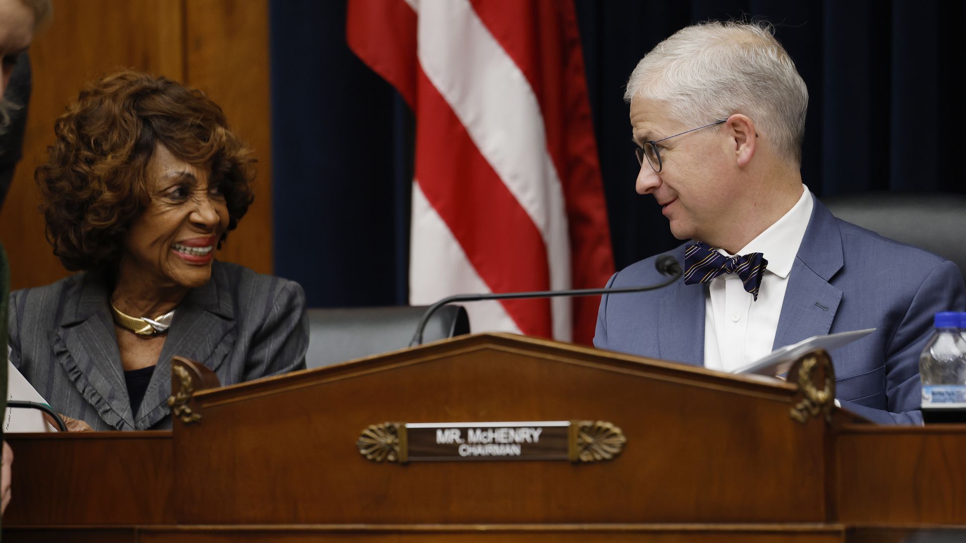 Maxine Waters and Patrick McHenry smile during a conversation.