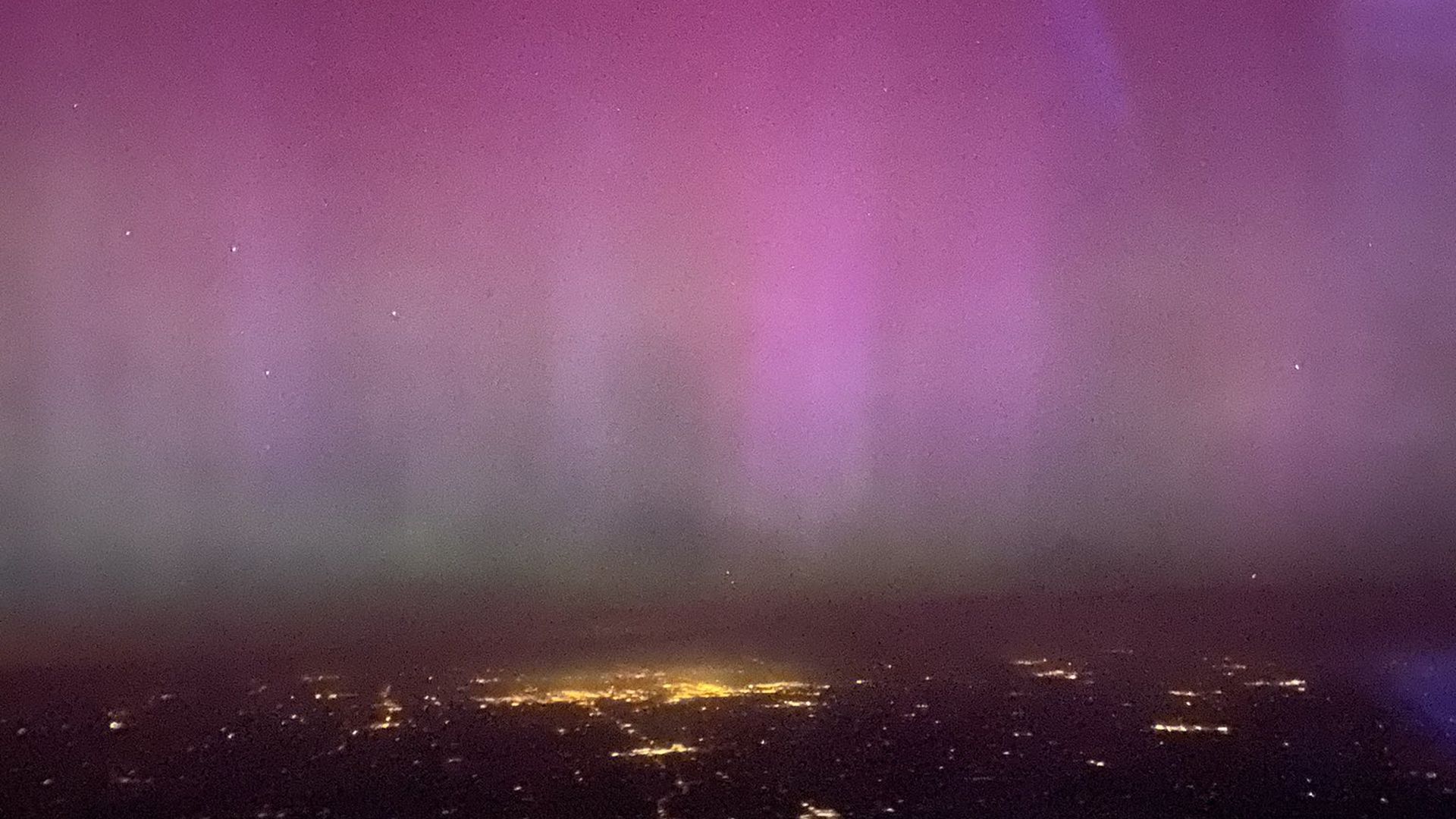 Pink aurora lights seen from a plane window