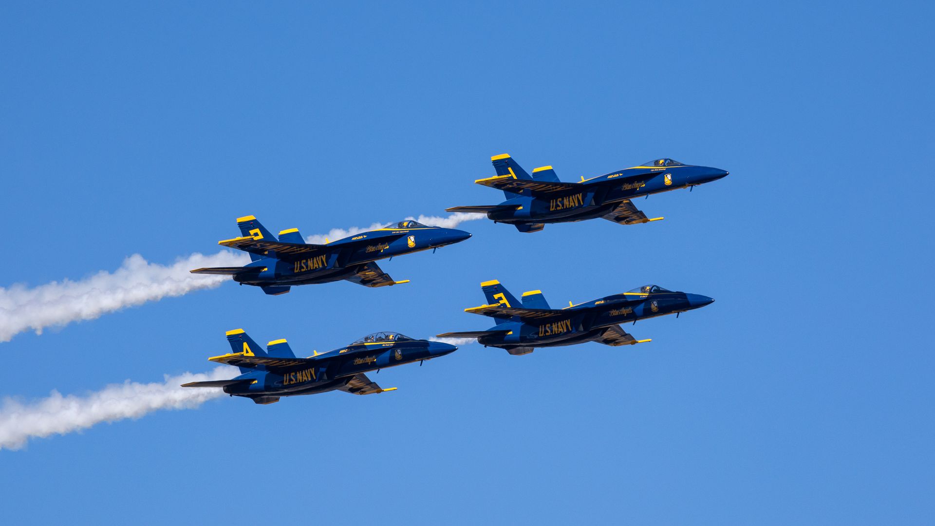 Four U.S. Navy jets fly through the air in sync.