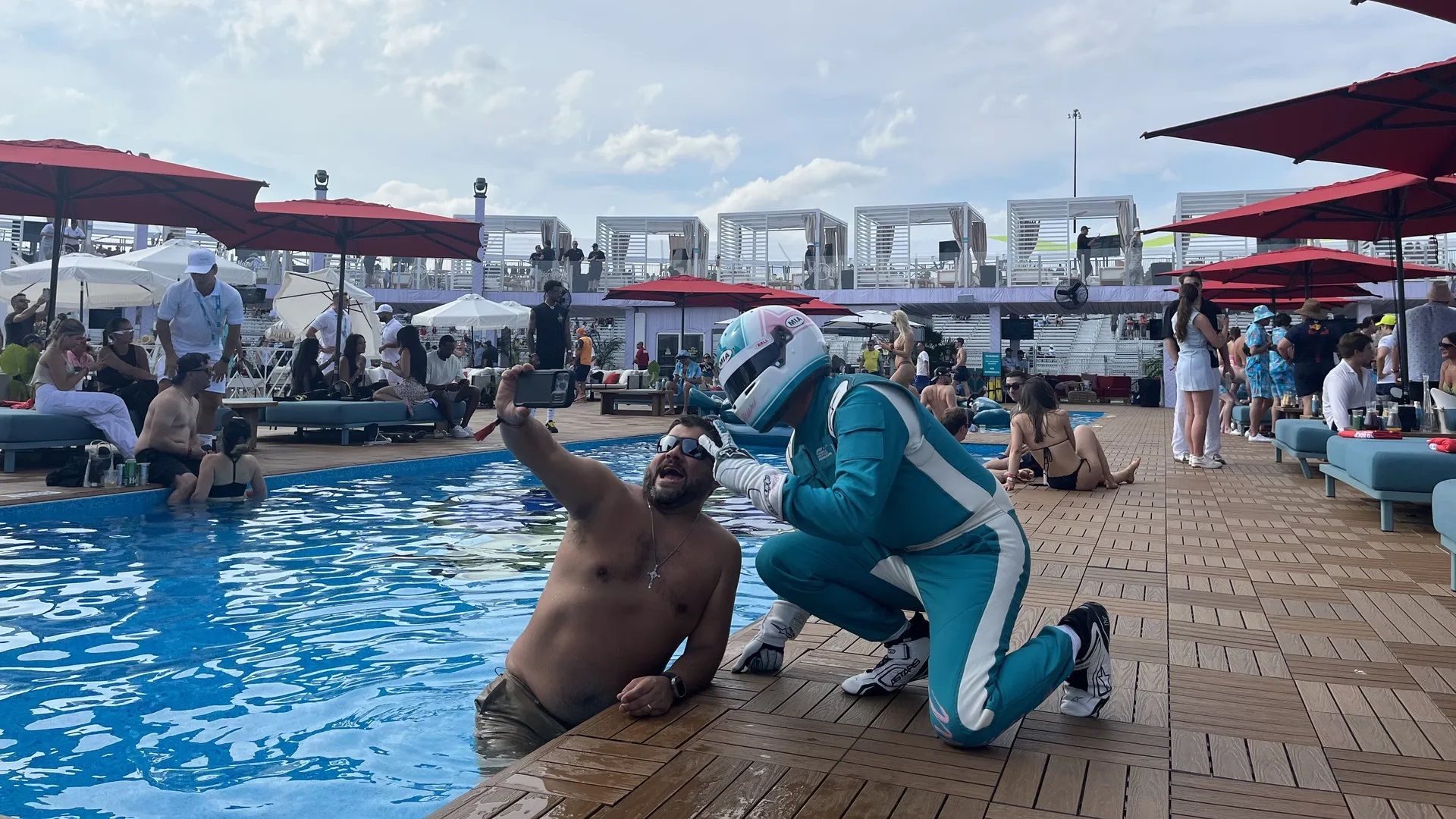 A man in a swimming pool takes a selfie with a driver at Miami's F1