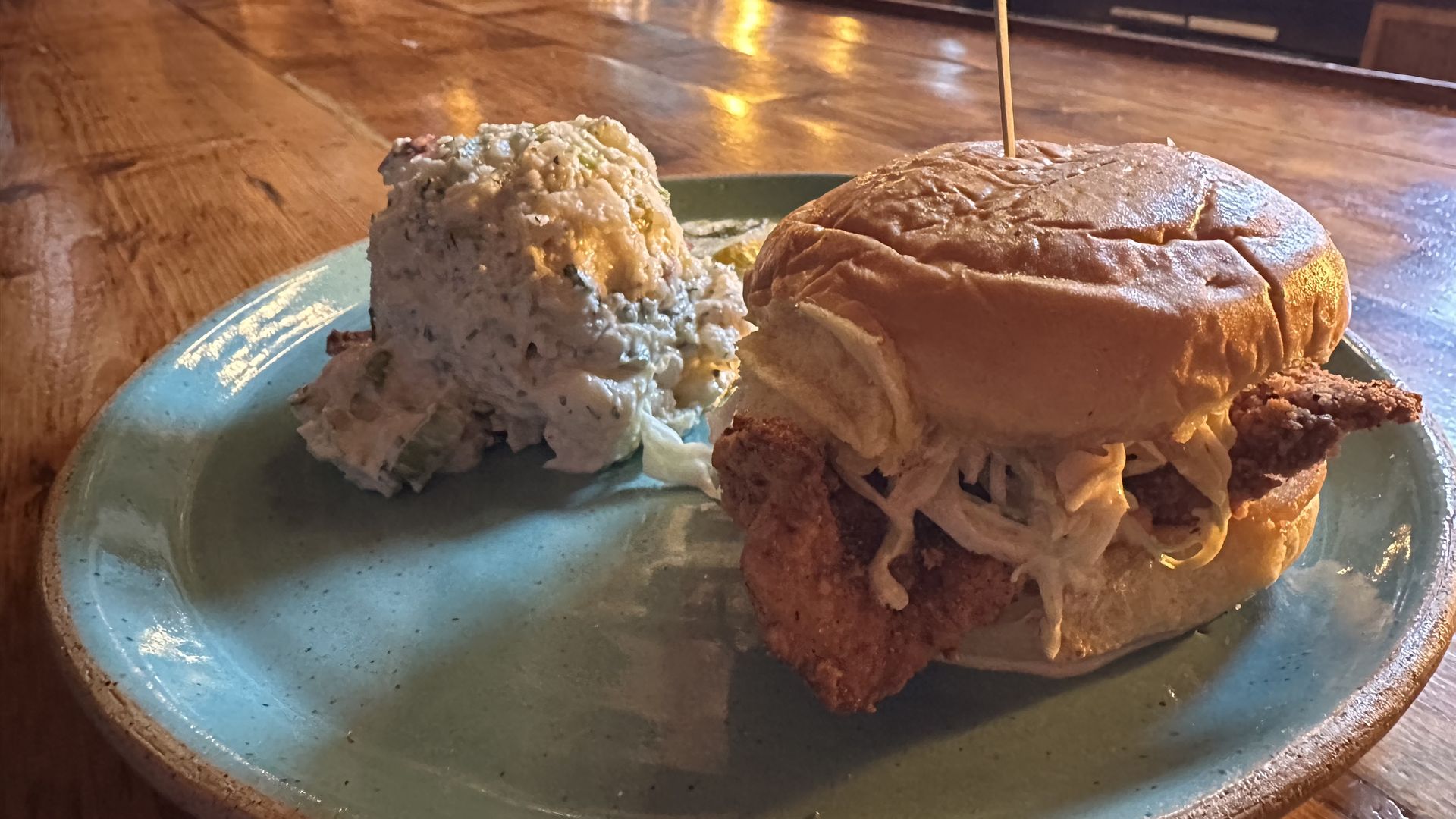 Fried chicken sandwich with potato salad on the bar counter at Hunter's in South Boston. 