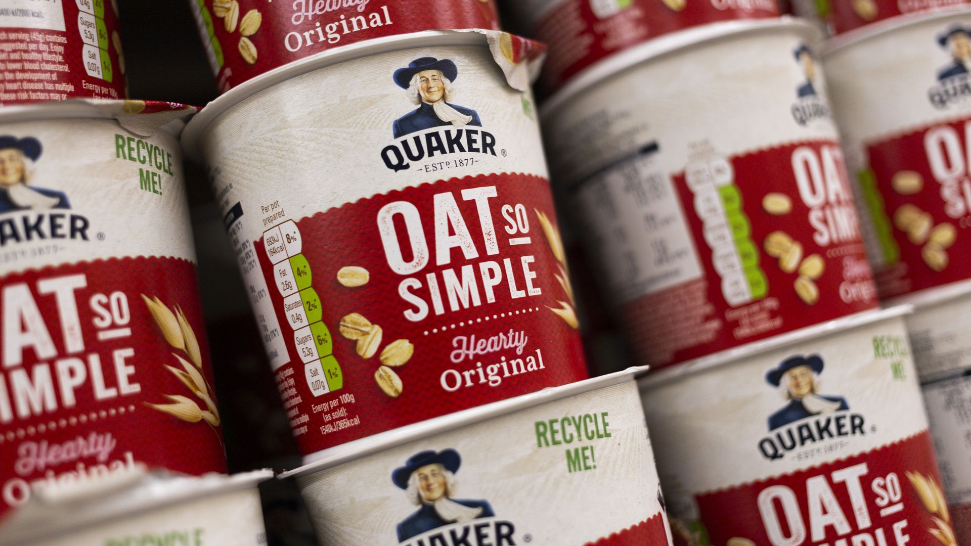 Quaker Oats products in round, red and white containers sit on a shelf.