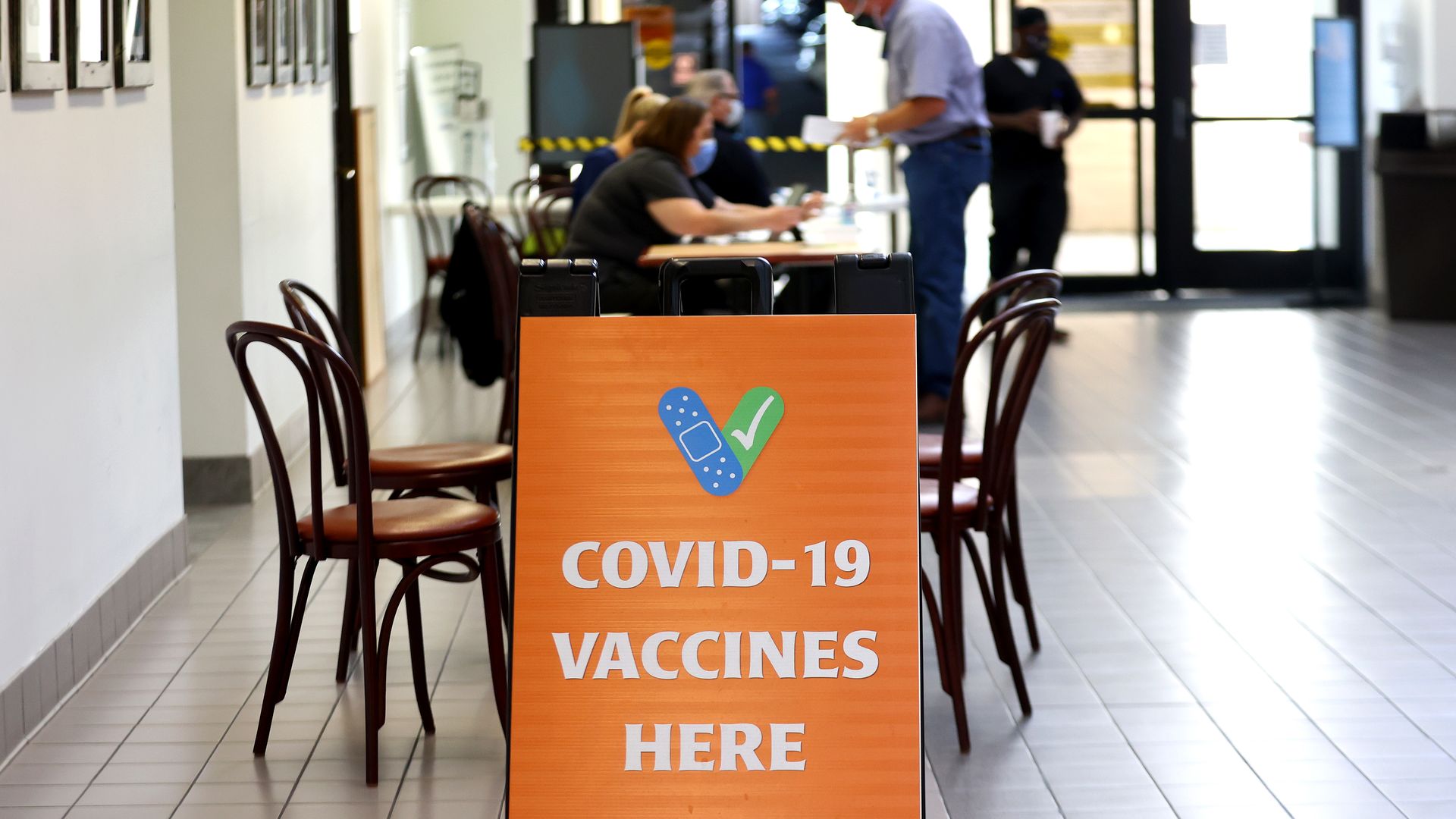 A hospital lobby with an orange sign that reads, "COVID-19 vaccines here."