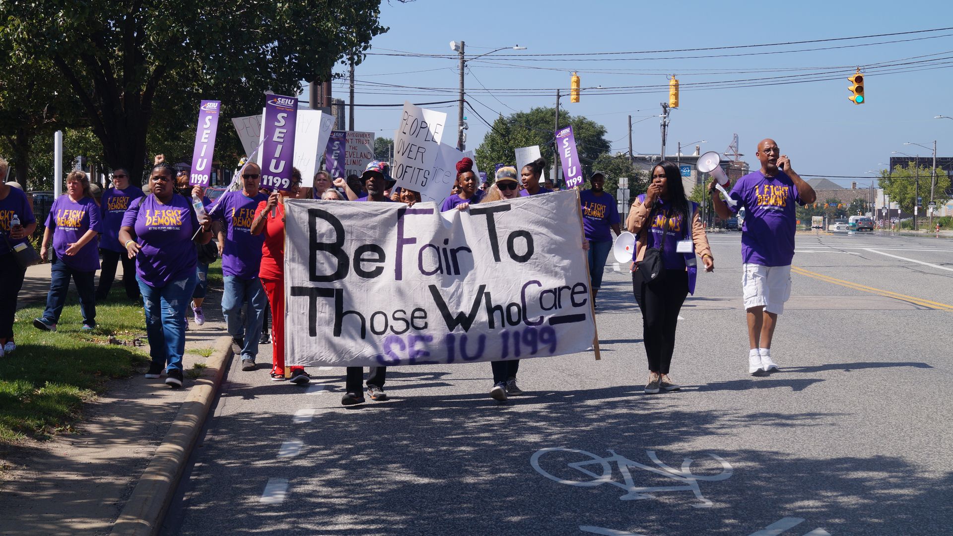 Members of SEIU 1199 march down Cleveland's W. 25th Street, holding sign reading, "Be Fair to Those Who Care"