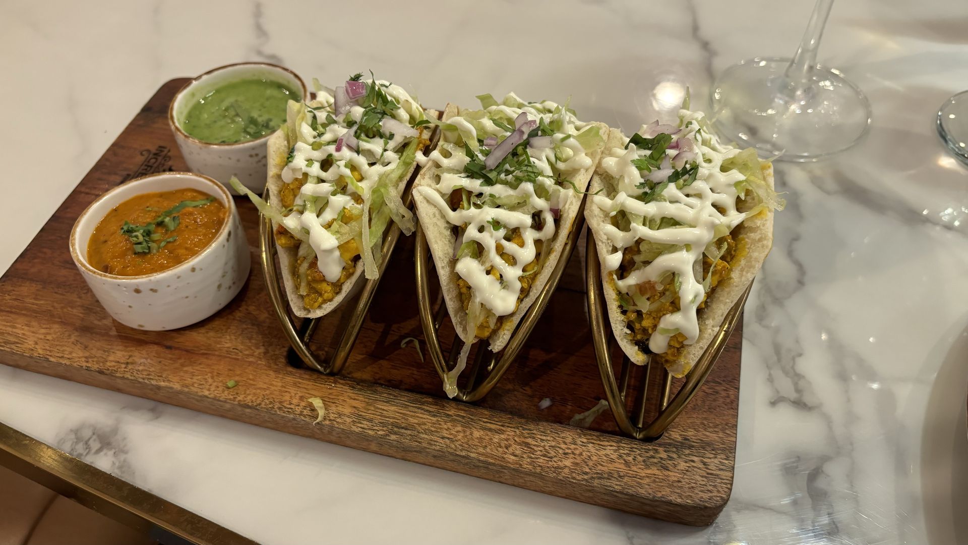Three tacos on a wooden board