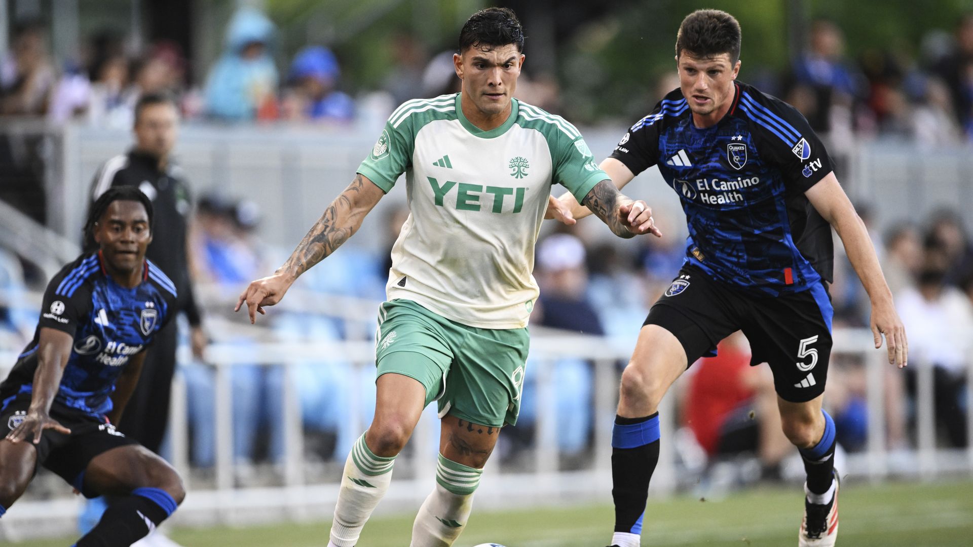 Austin FC player Brandon Vázquez dribbles a soccer ball while looking down while two players from the San Jose Earthquakes chase him. 