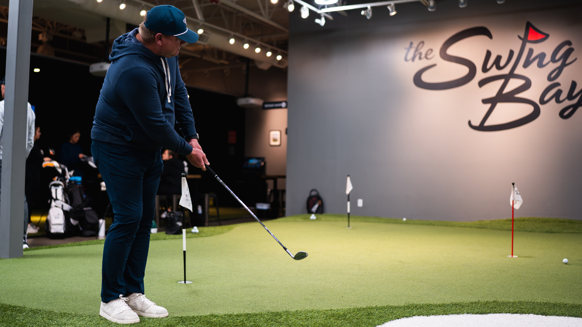 a man chips at an indoor putting green