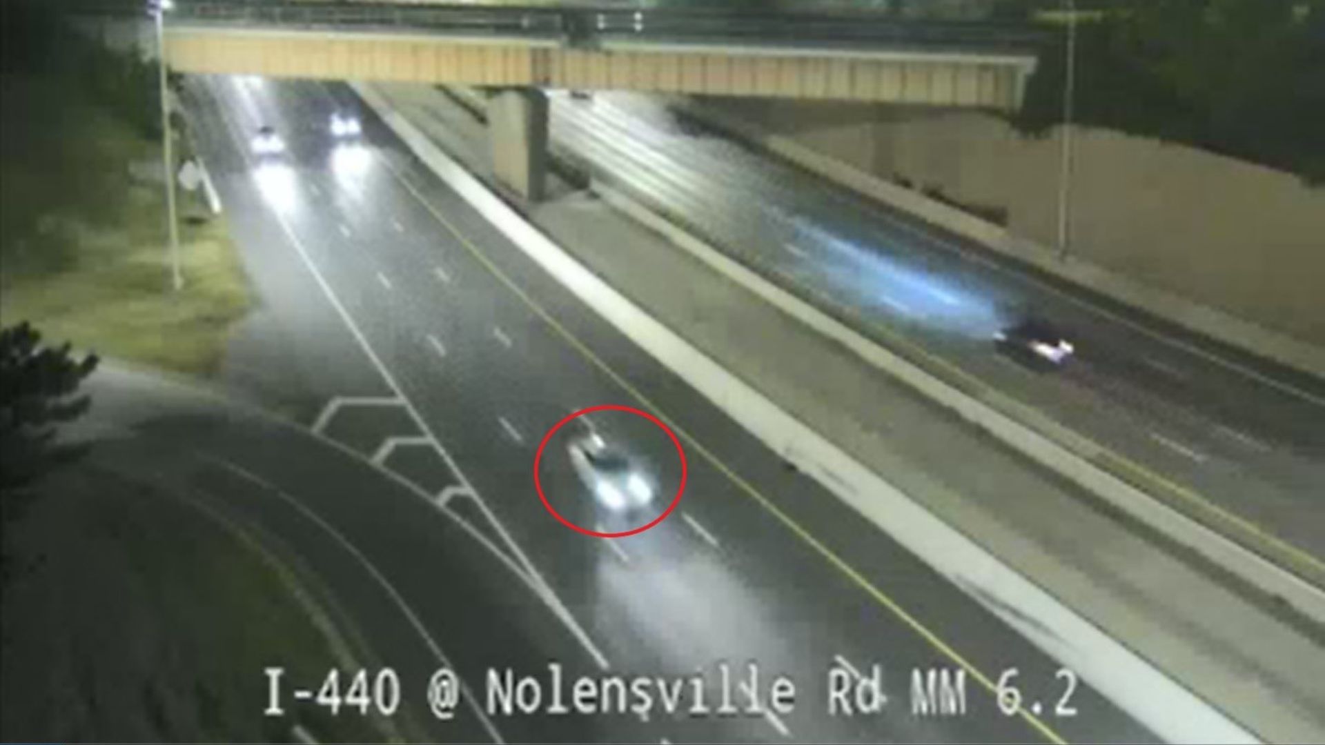 A picture showing a white sedan driving on the interstate.