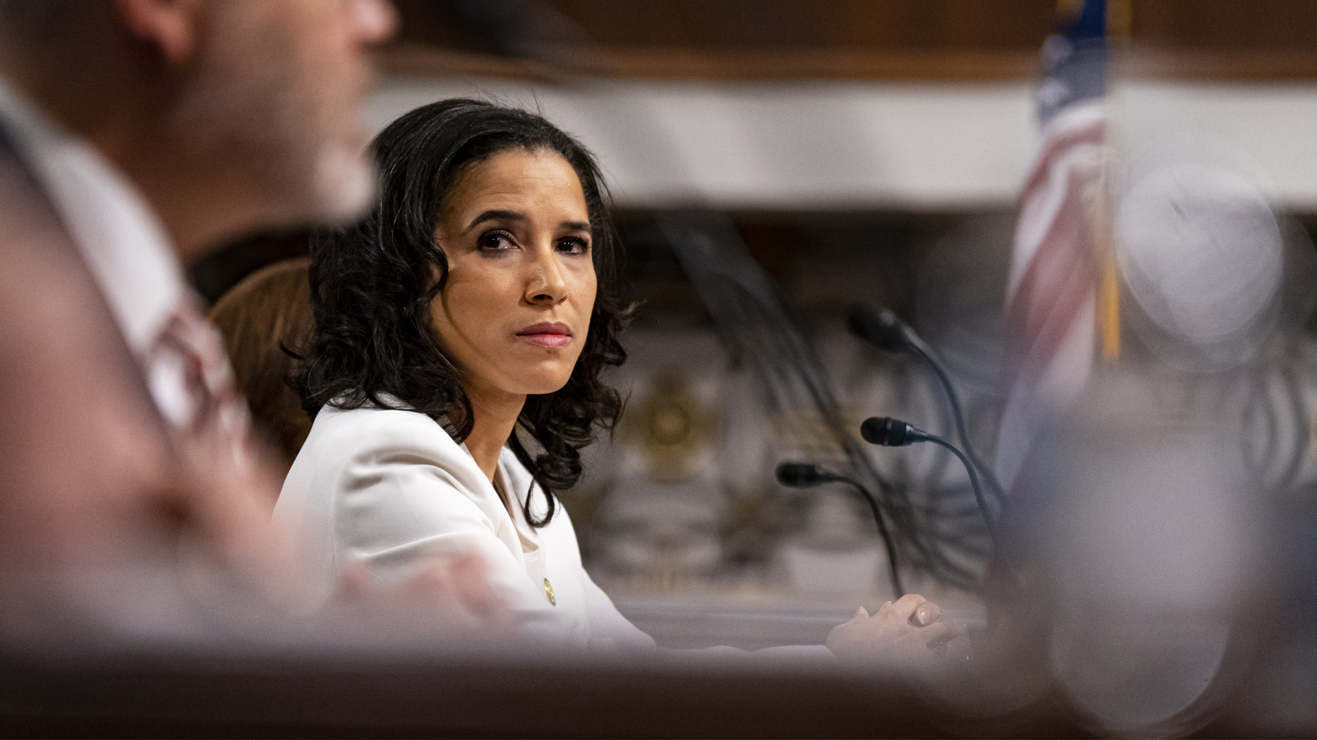 A woman listens to another speaker during a hearing in an official capacity.