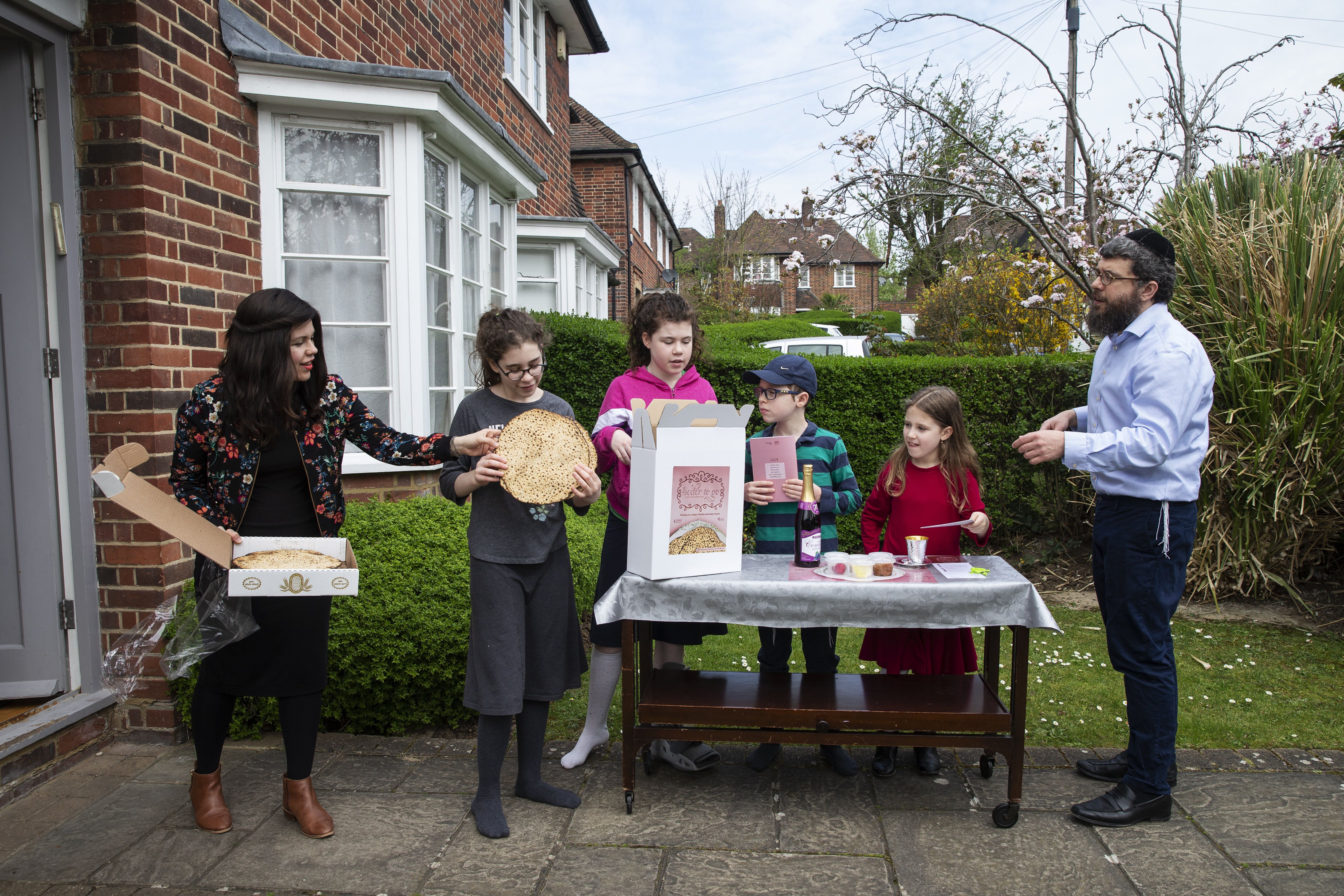In this image, kids and adults hold food at a small table outside a house