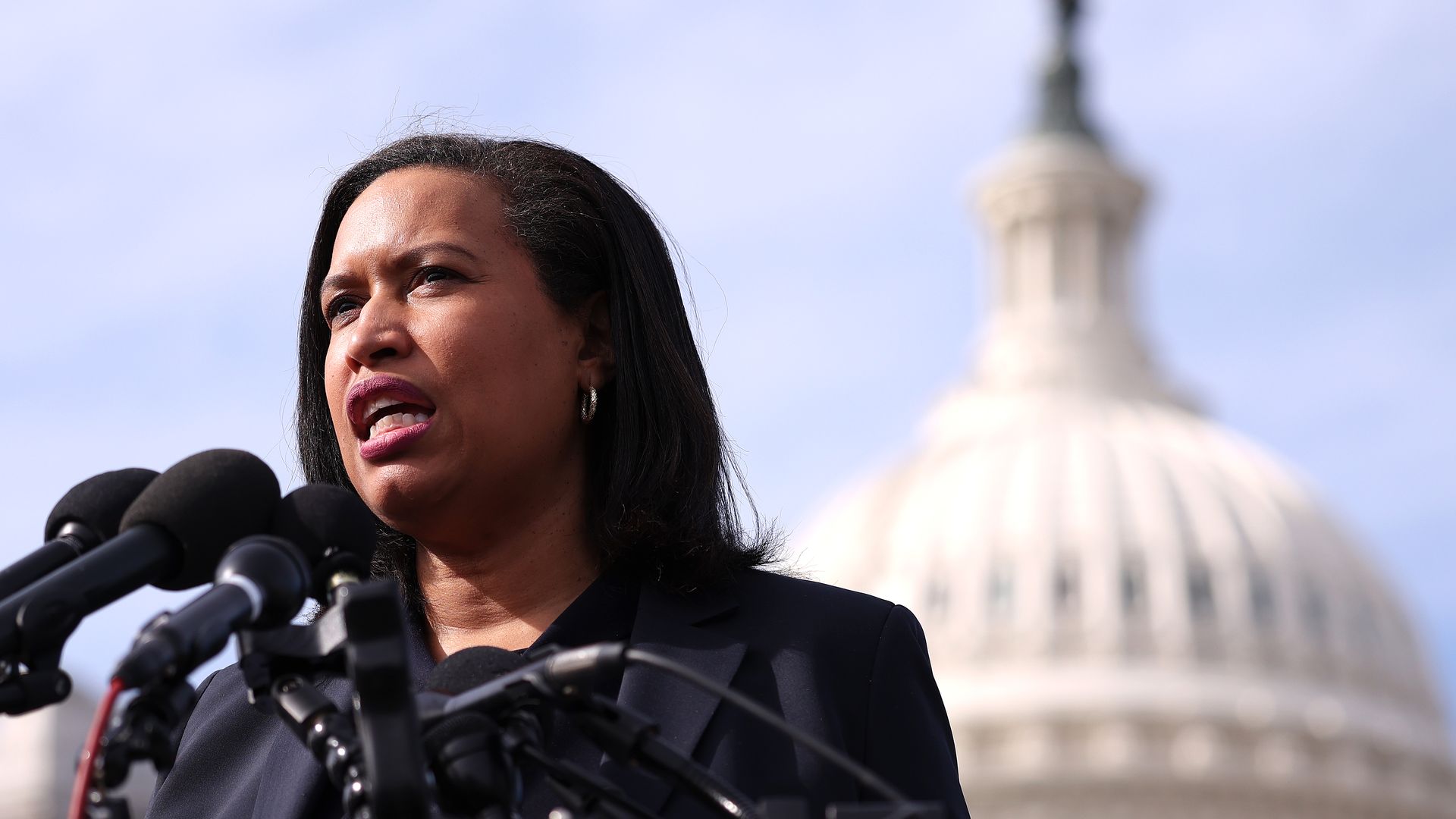 Muriel Bowser speaks to microphones with the Capitol in the background