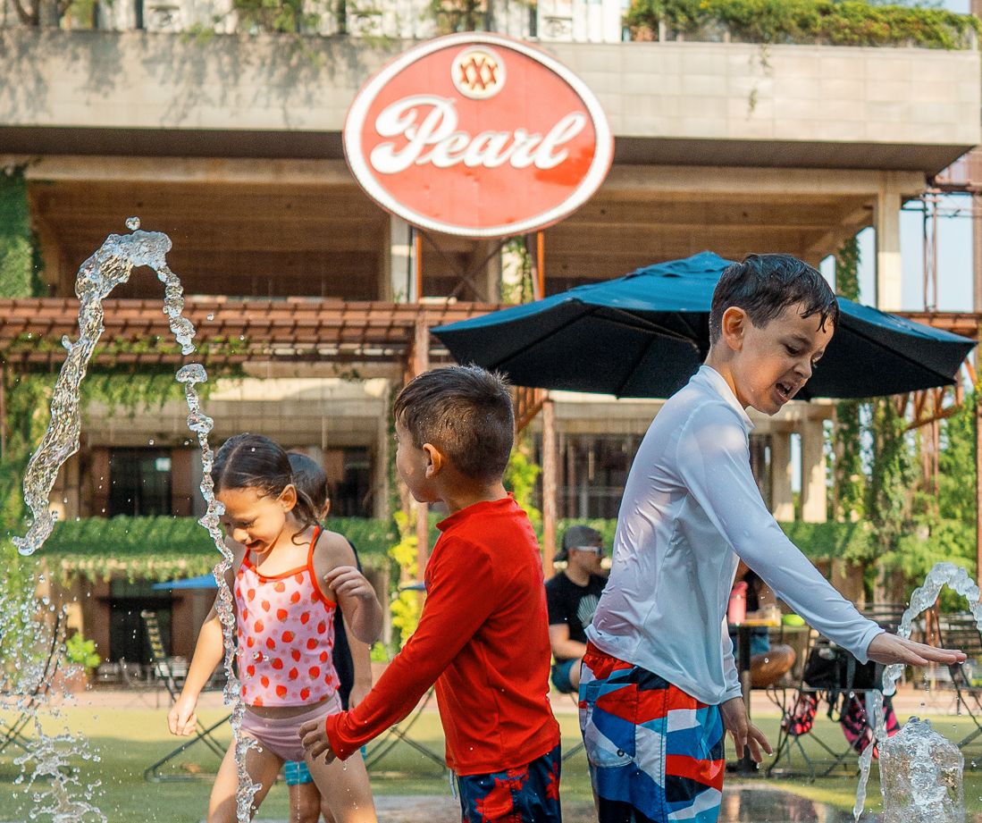 Three children play in a splash pad. 