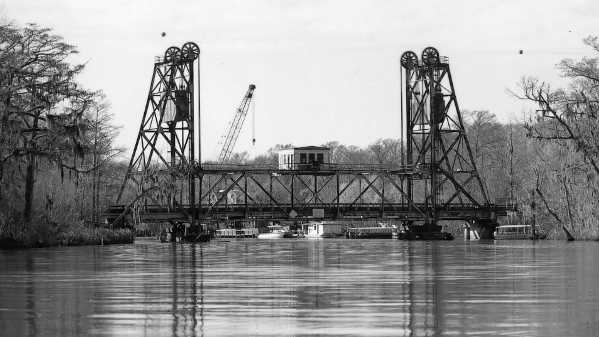 A black and white image of a bridge over water.