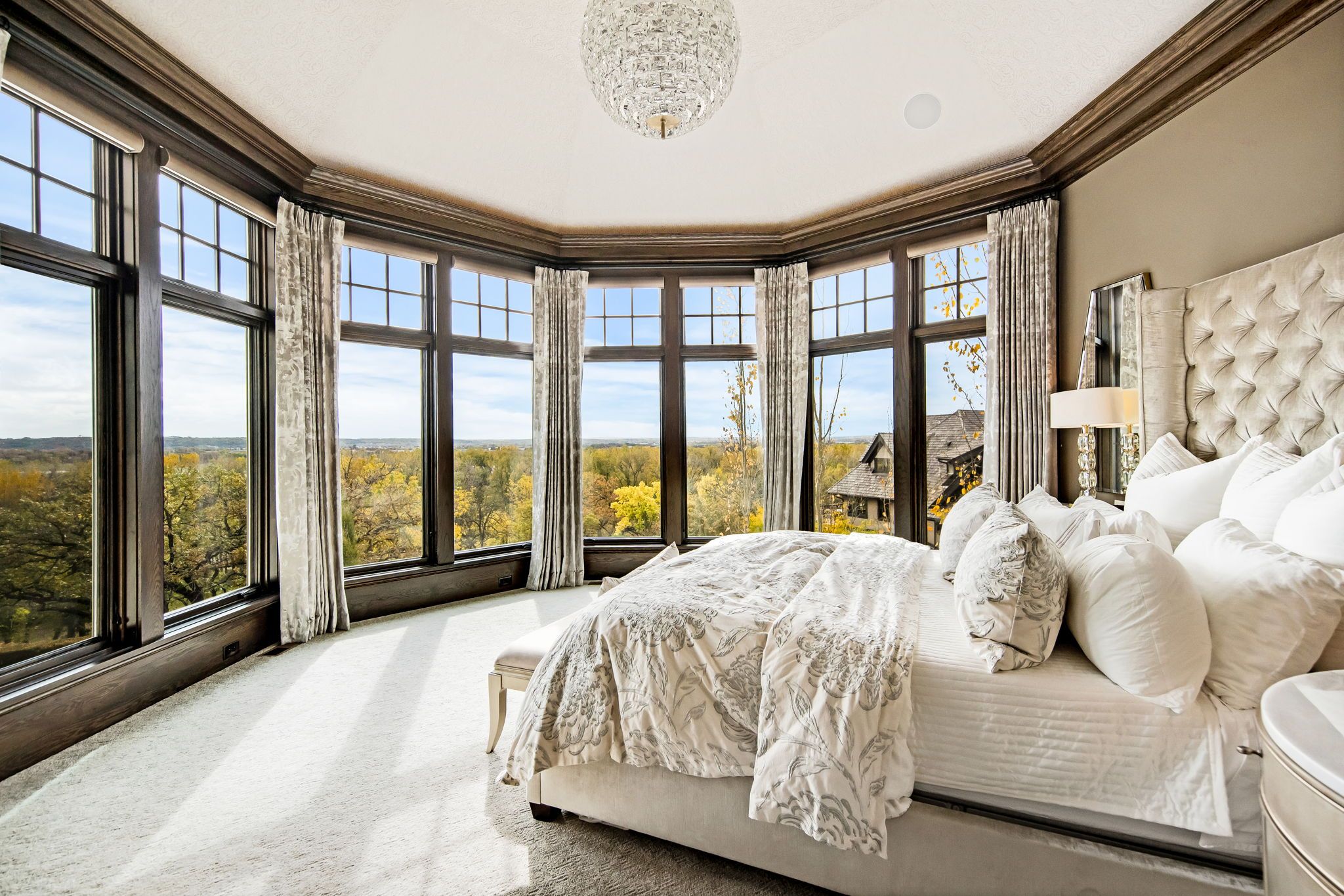 A bedroom with curved windows showing views of the river valley.