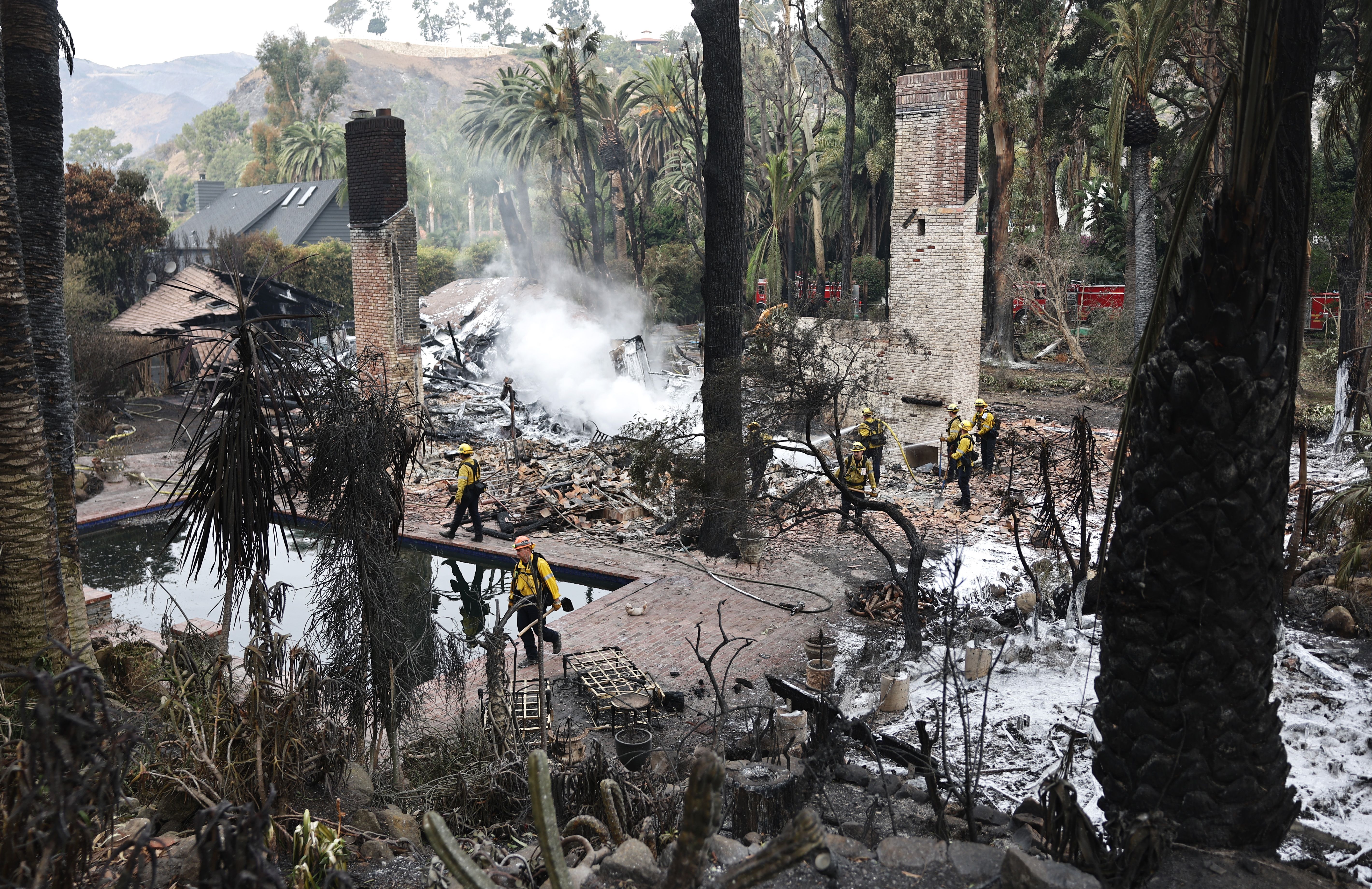  Los Angeles County Fire Department firefighters work to put out hotspots at a home destroyed in the Franklin Fire on December 11, 2024 in Malibu, California. 