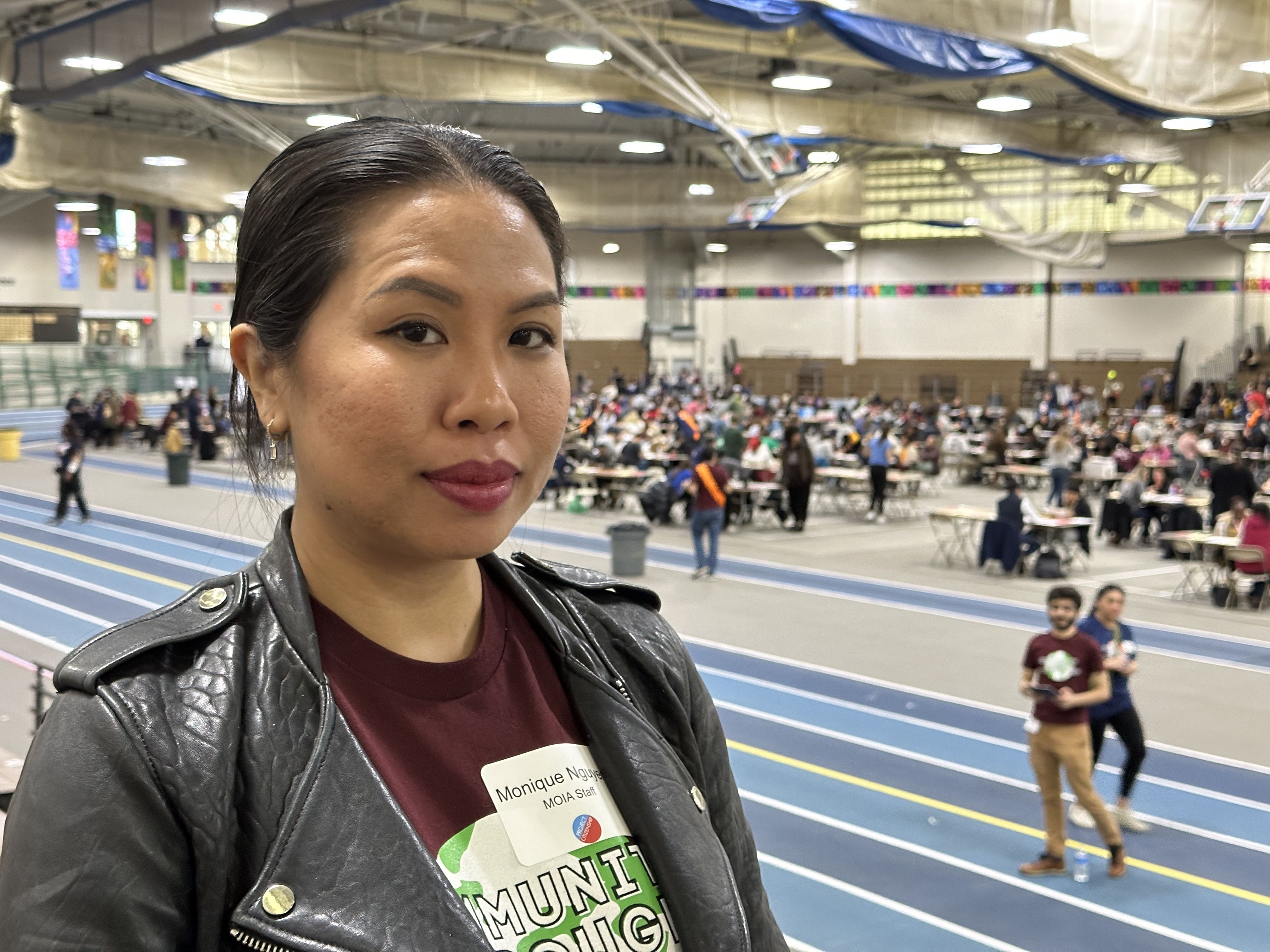 Monique Nguyen, executive director of the city's office for immigrant advancement, stands in the bleachers. The citizenship clinic is visible in the background.