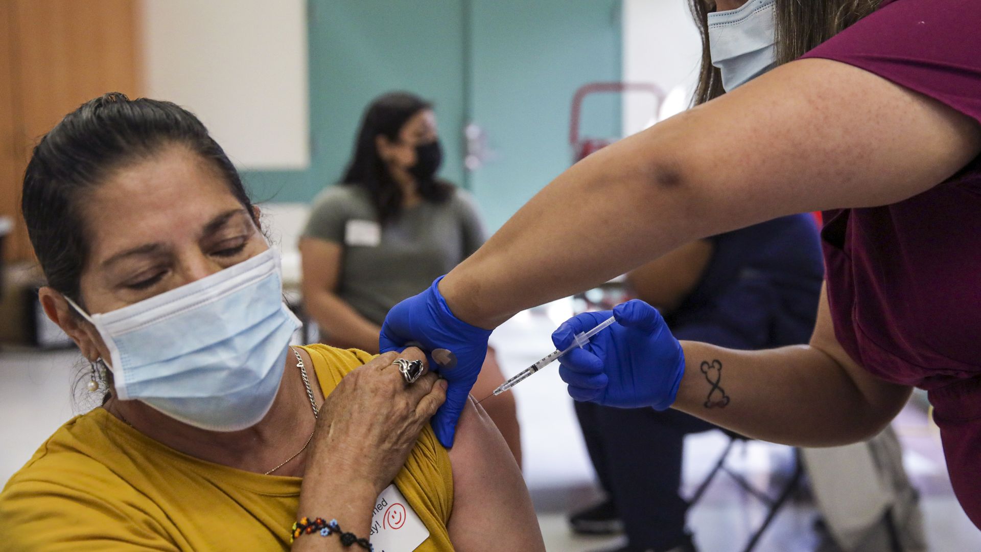 Photo of a masked person getting a COVID vacine shot in their left arm
