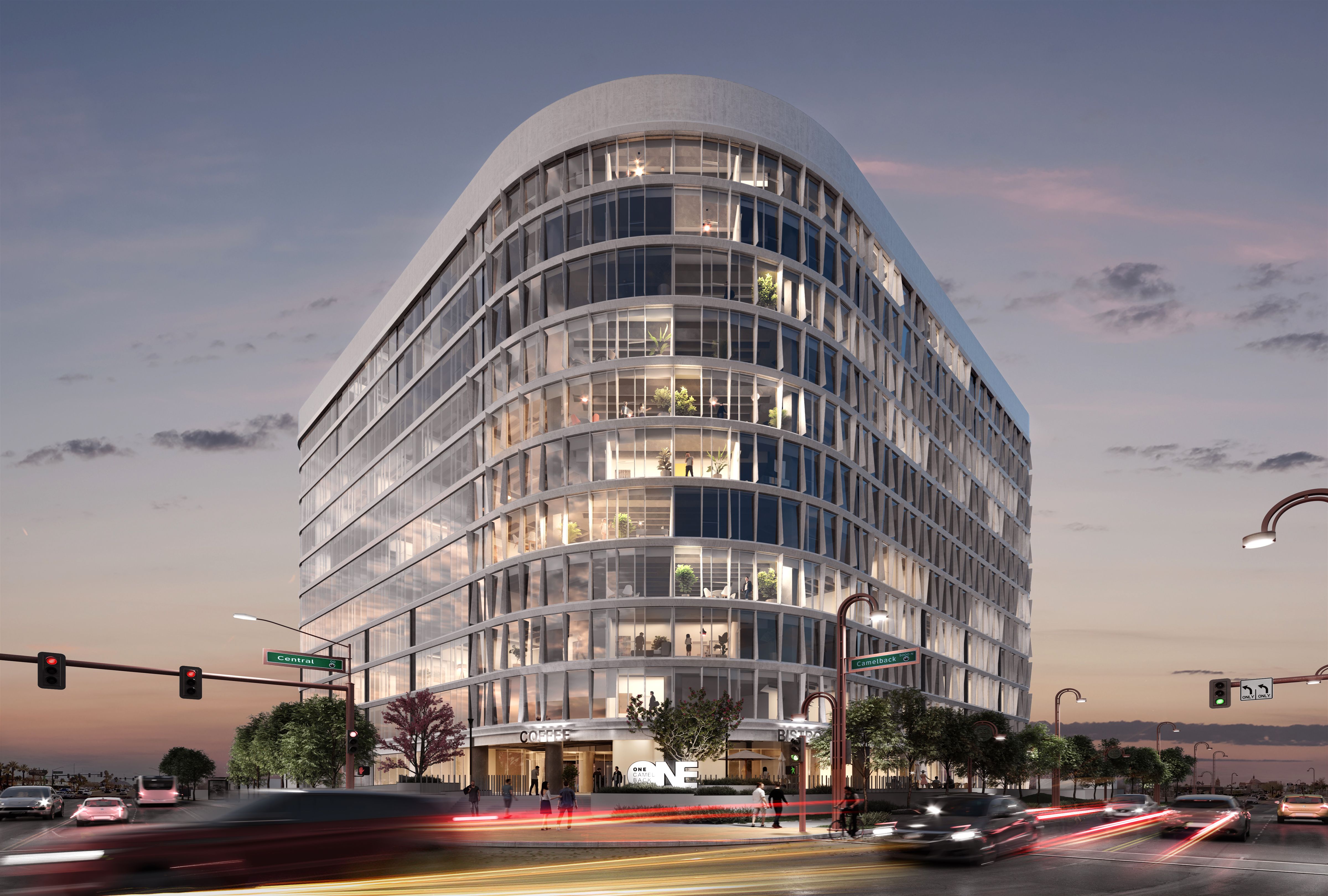 Modern glass office building at dusk with rounded corners, illuminated interior, street signs for Central and Camelback, cars with light trails, and pedestrians on sidewalks.