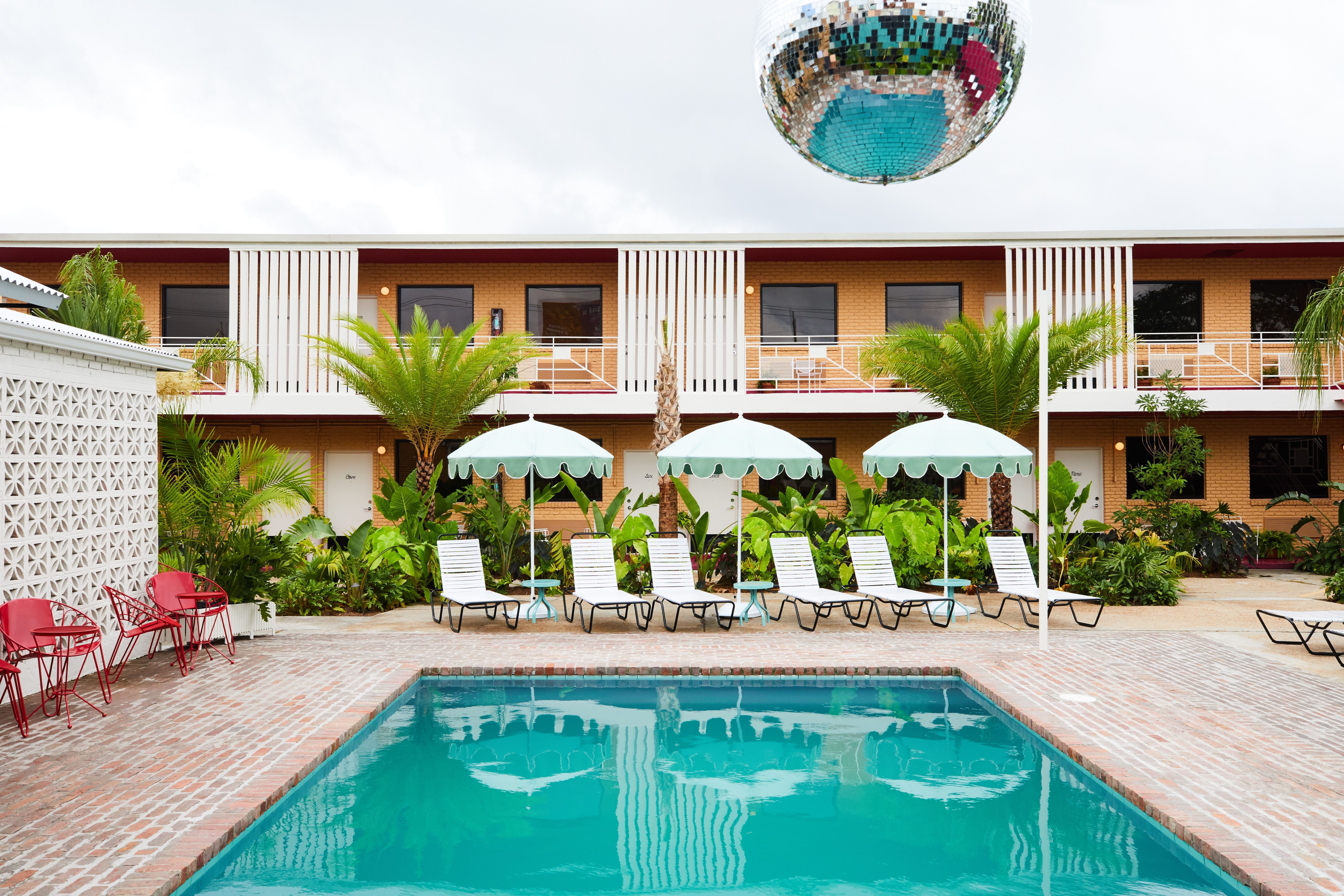 A modern-designed hotel pool with room doors in the background.