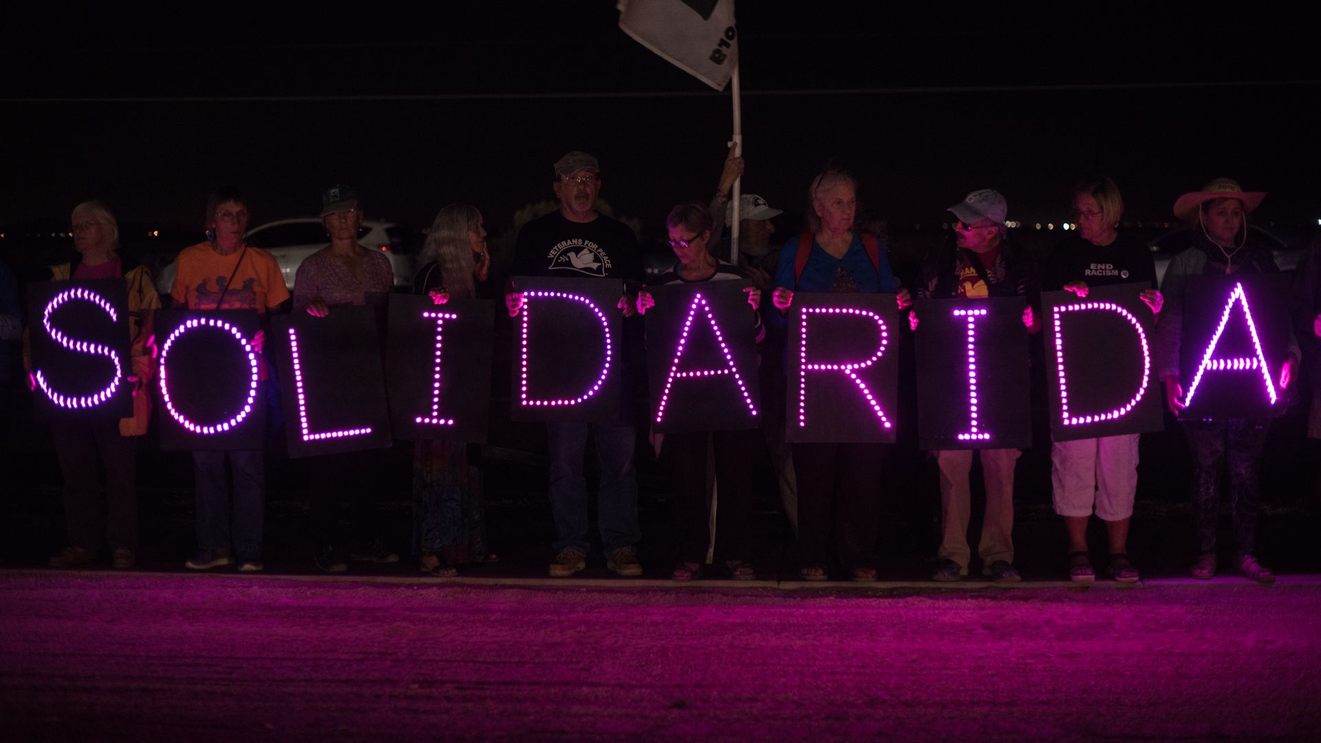 Group of protestors in the dark hold a lowing sign that says "solidarida"