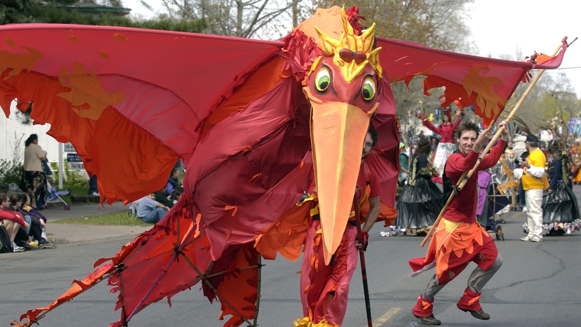 An enormous red bird puppet, which is as tall as an average man and at least 10 feet wide.