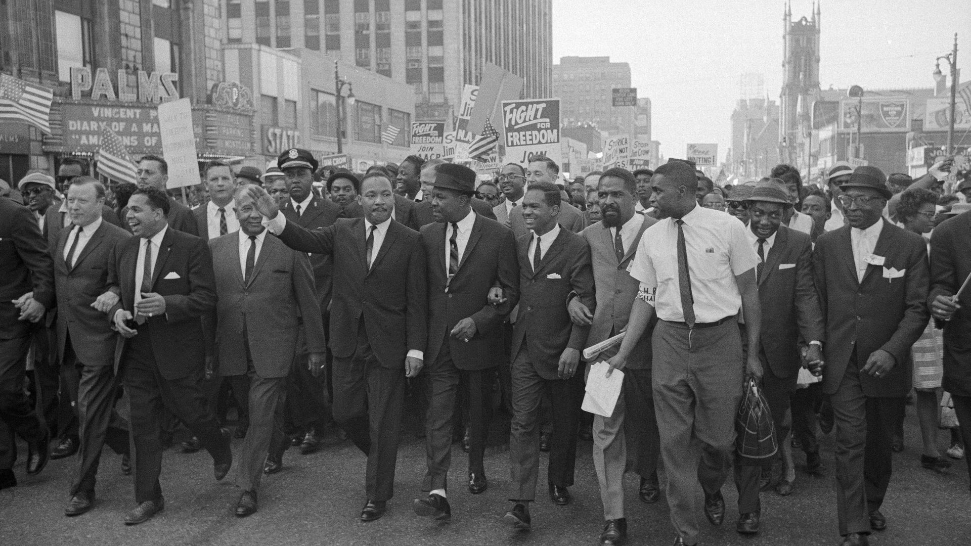 Martin Luther King Jr. is pictured among a huge group of people marching in Detroit, waving. 