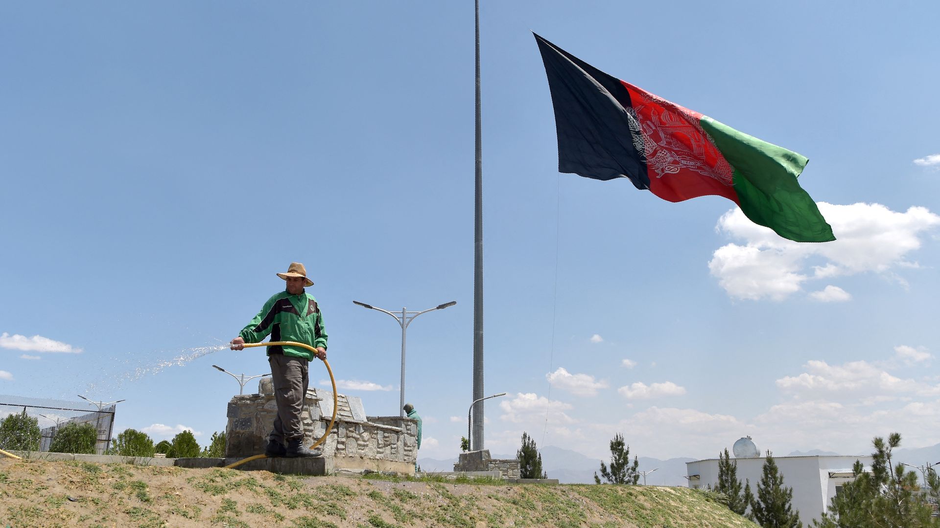 Photo of an Afghan flag flying at half-mast against a blue sky