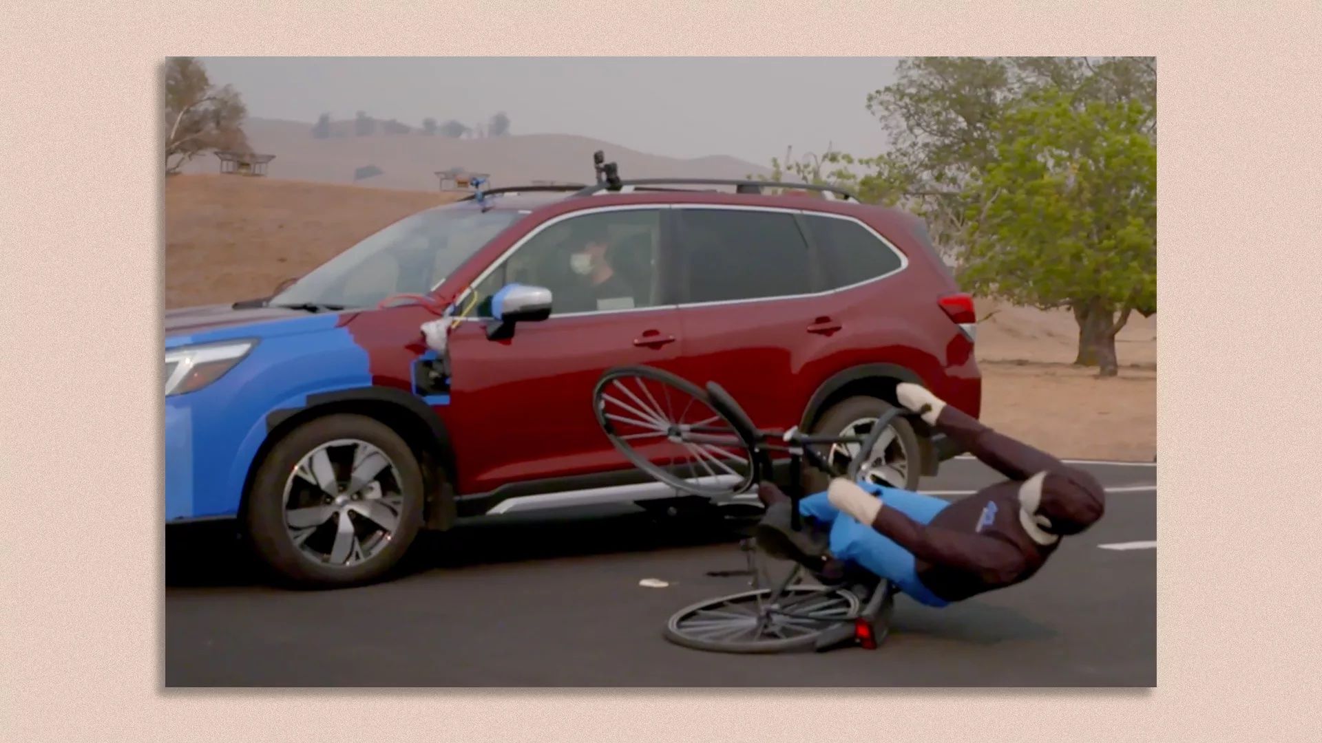 A crash test dummy on a bike getting knocked over by an automated car