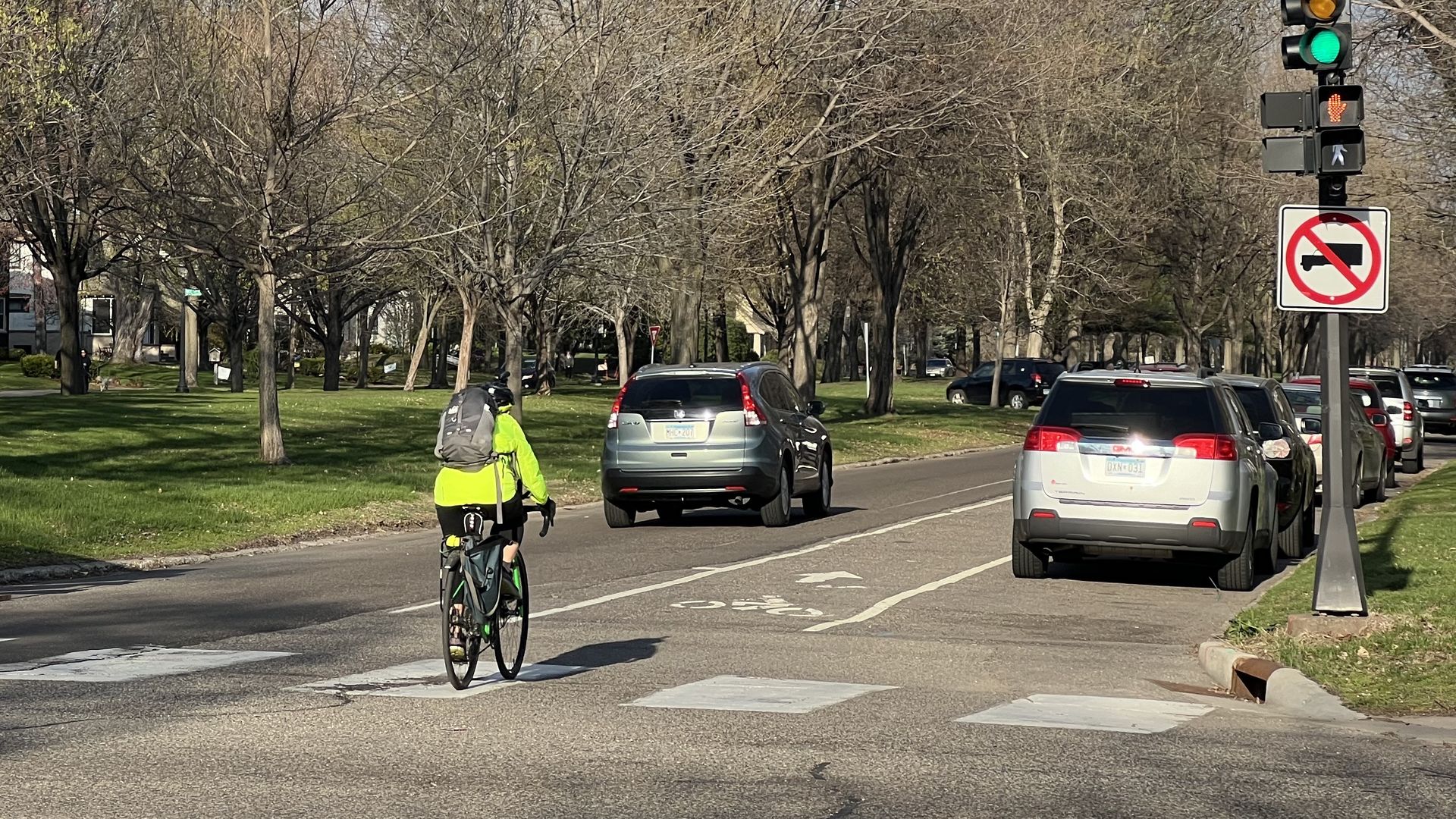 A cyclist in a neon jacket rides a bicycle down an on-street bicycle lane.