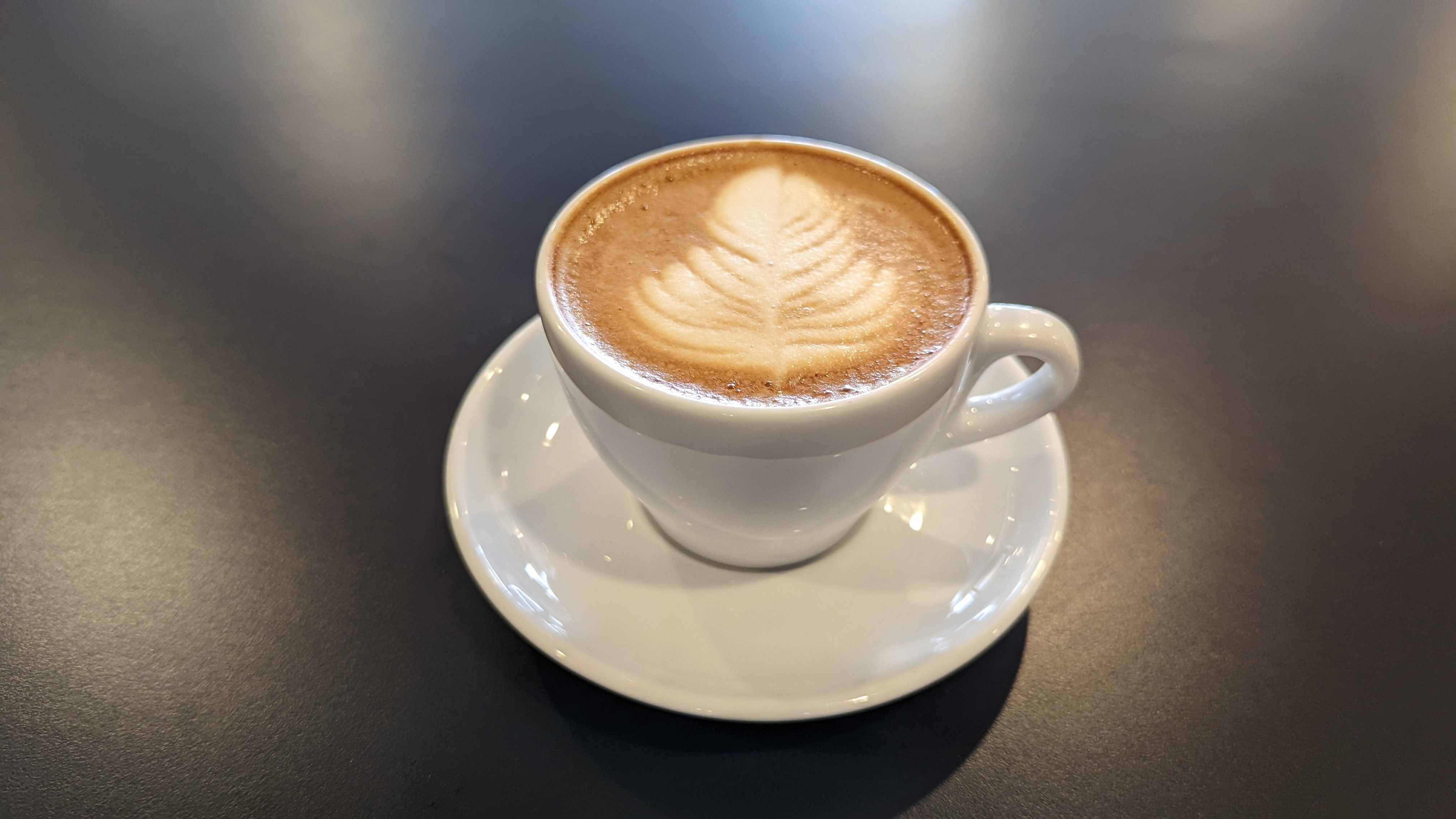 A latte with milk foam drizzled in the shape of a tree.