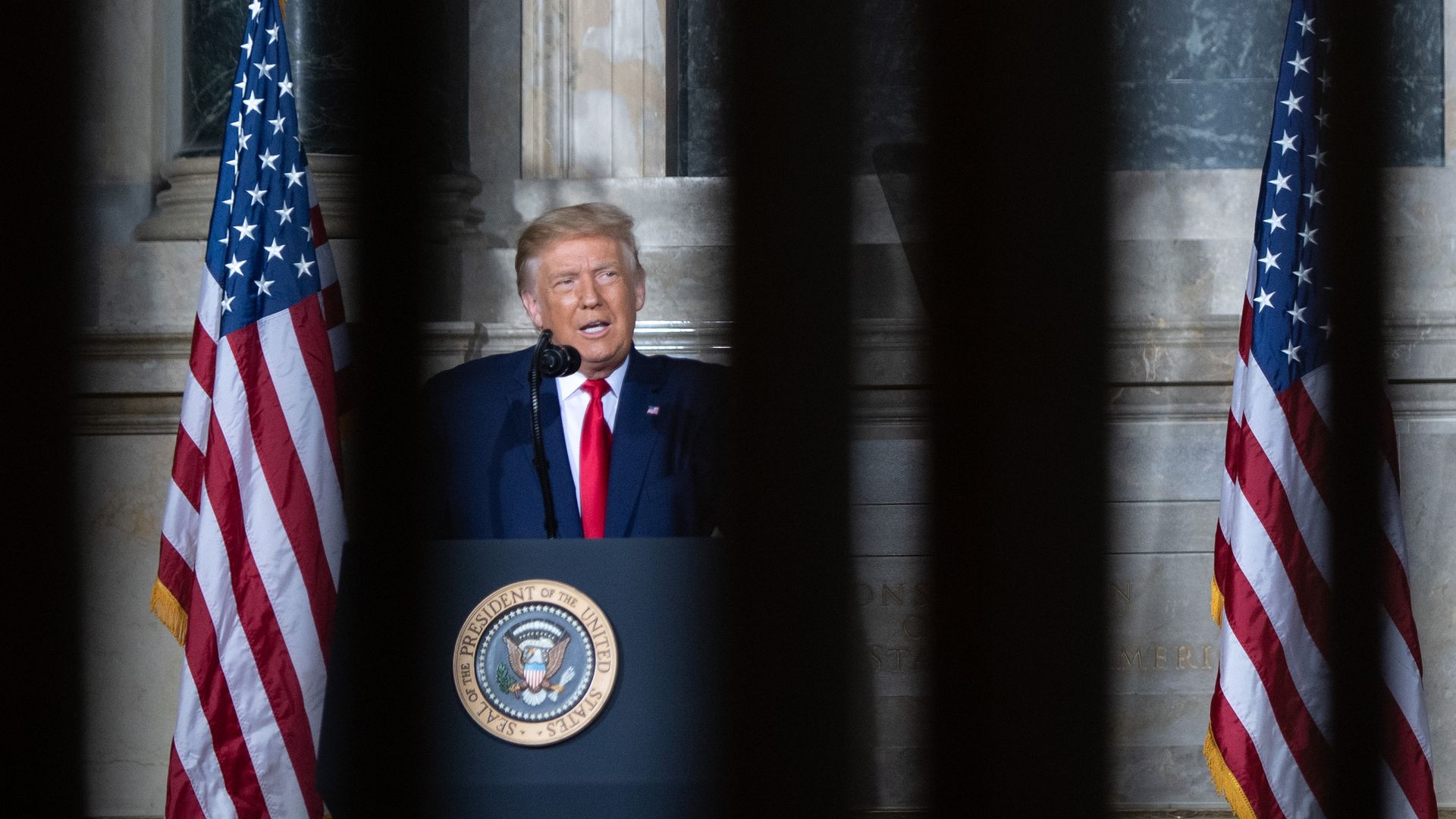 Trump at a podium with American flags nearby