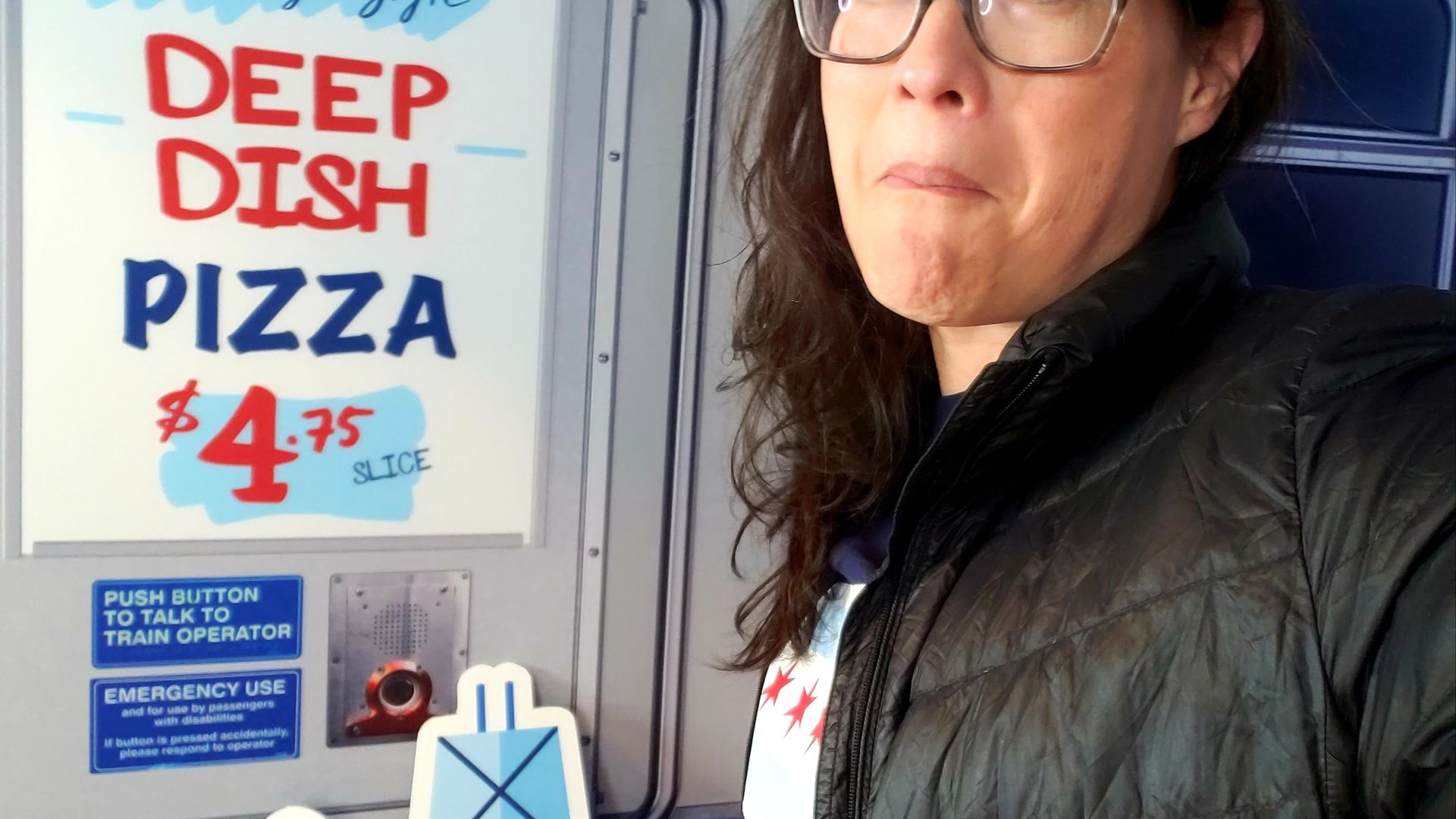 Photo of a woman standing next to a poster for deep dish pizza.