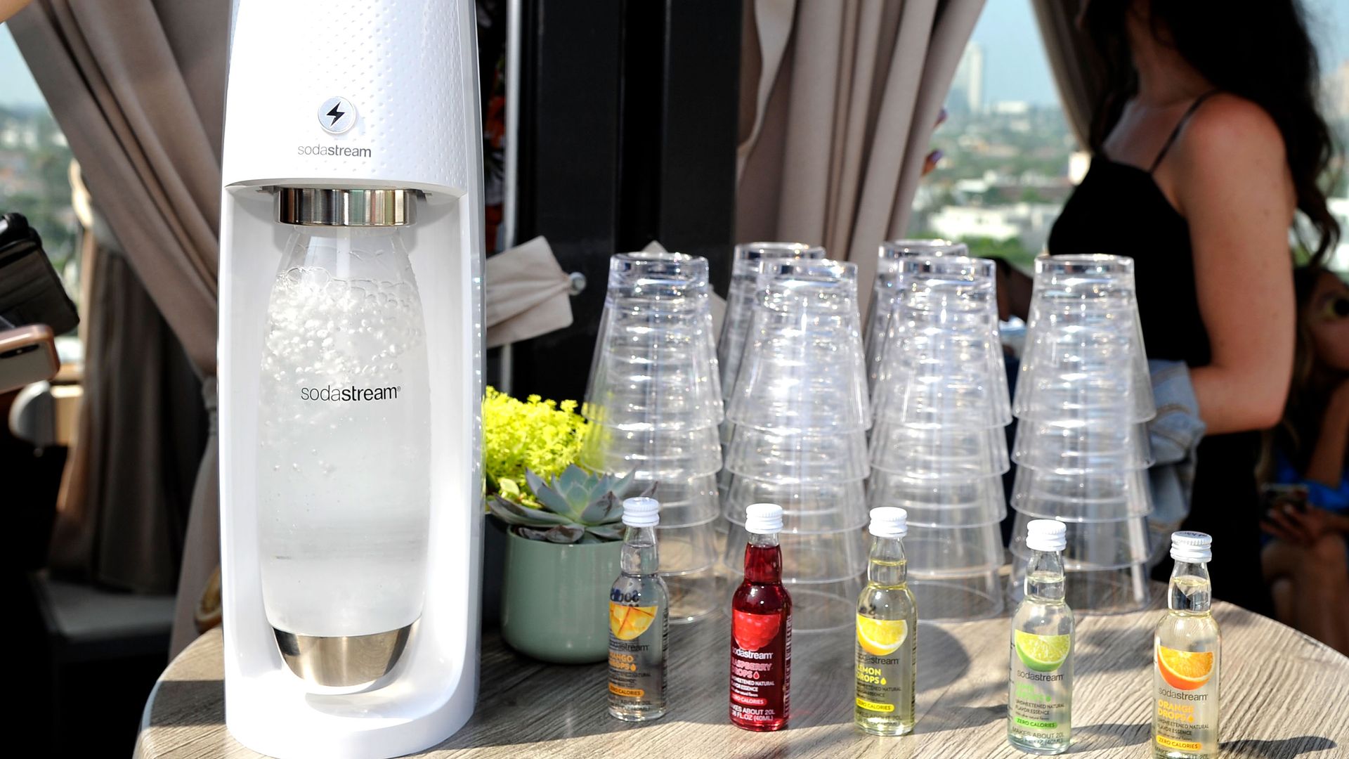 A hand activating a SodaStream device to carbonate a drink. 