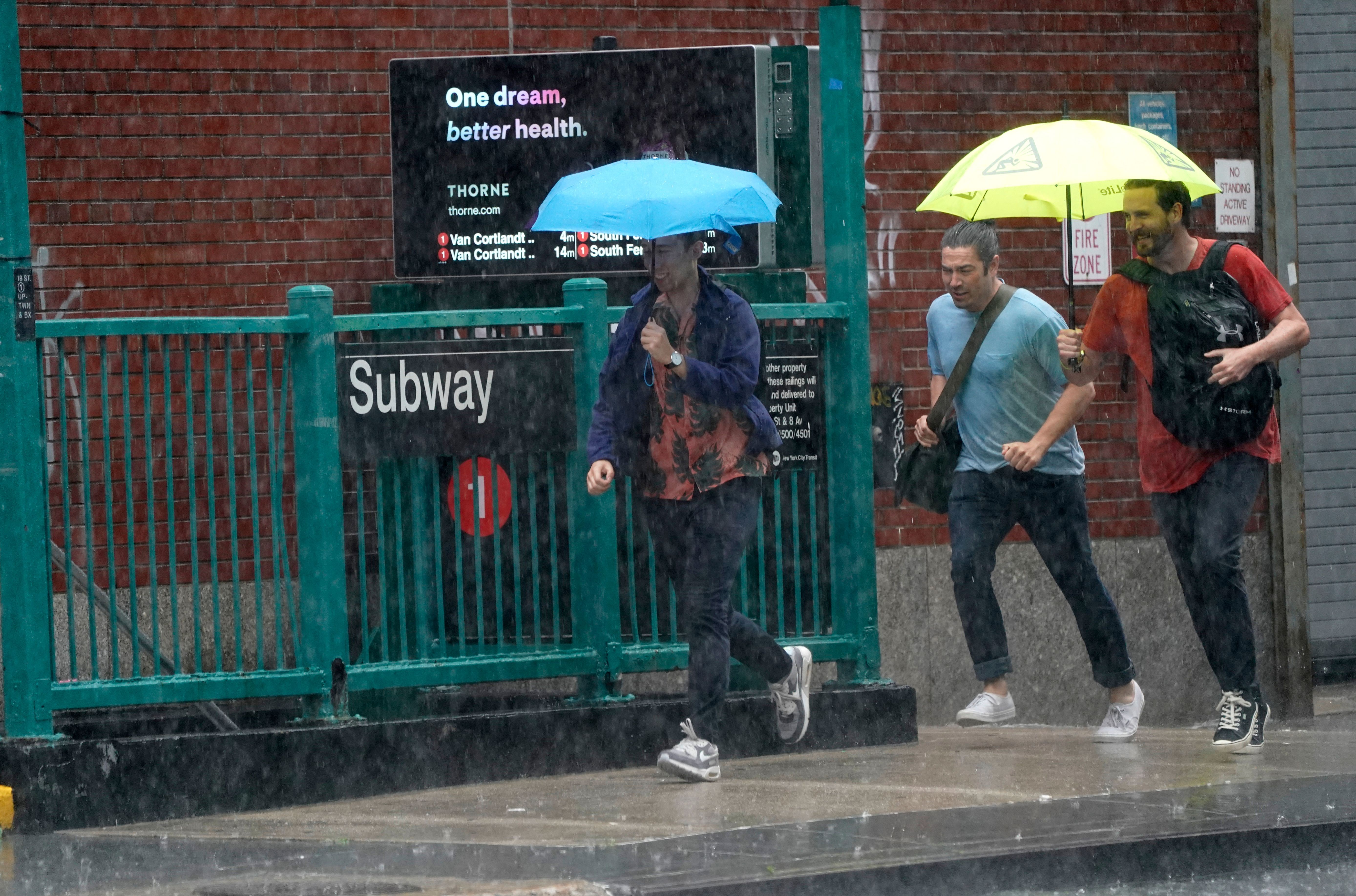 People running from the rain in New York, by a subway stop