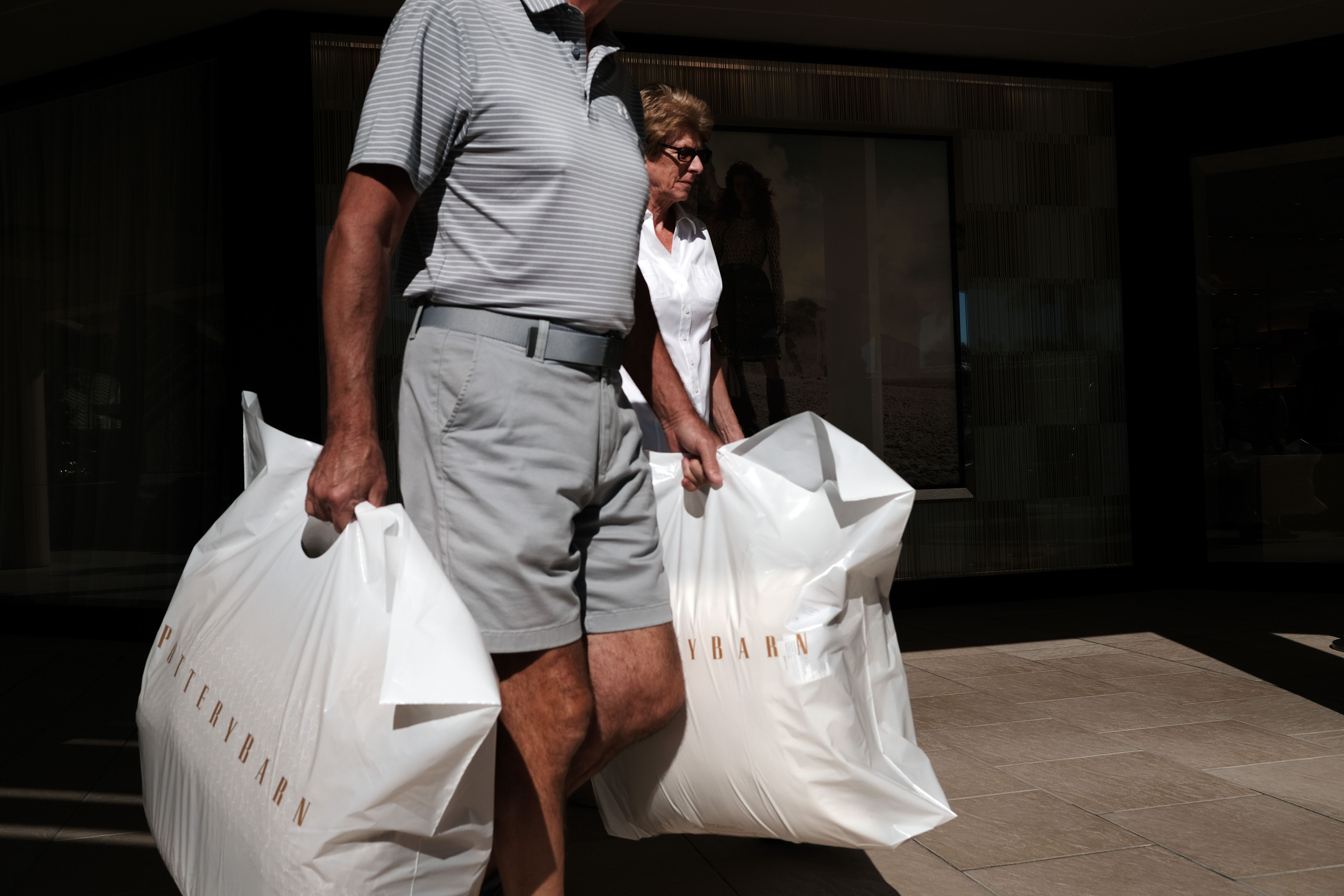 a man holding two stuffed pottery barn bags