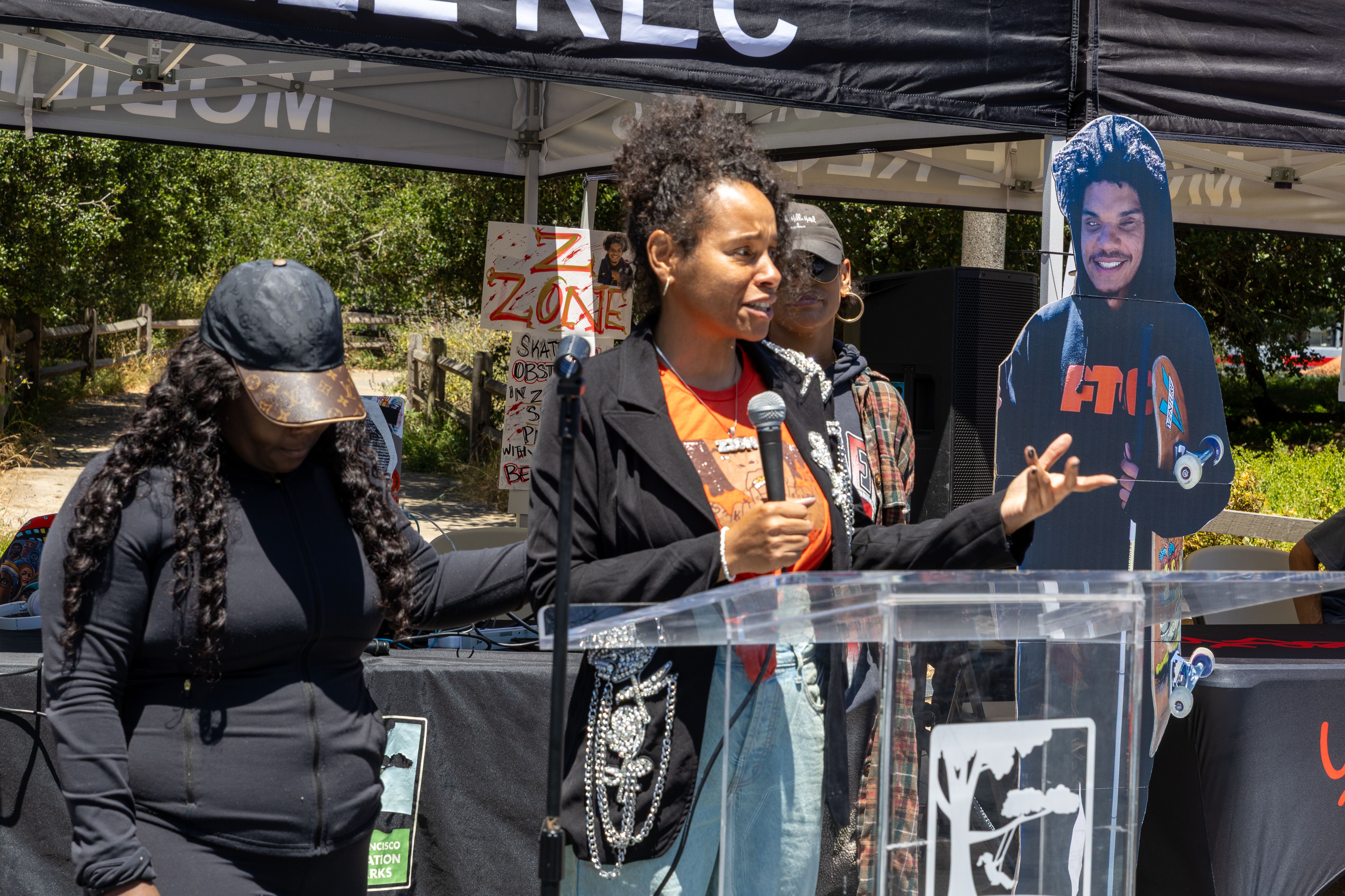Photo of a person speaking at a podium next to a cardboard cutout of Zion Williams Gaines