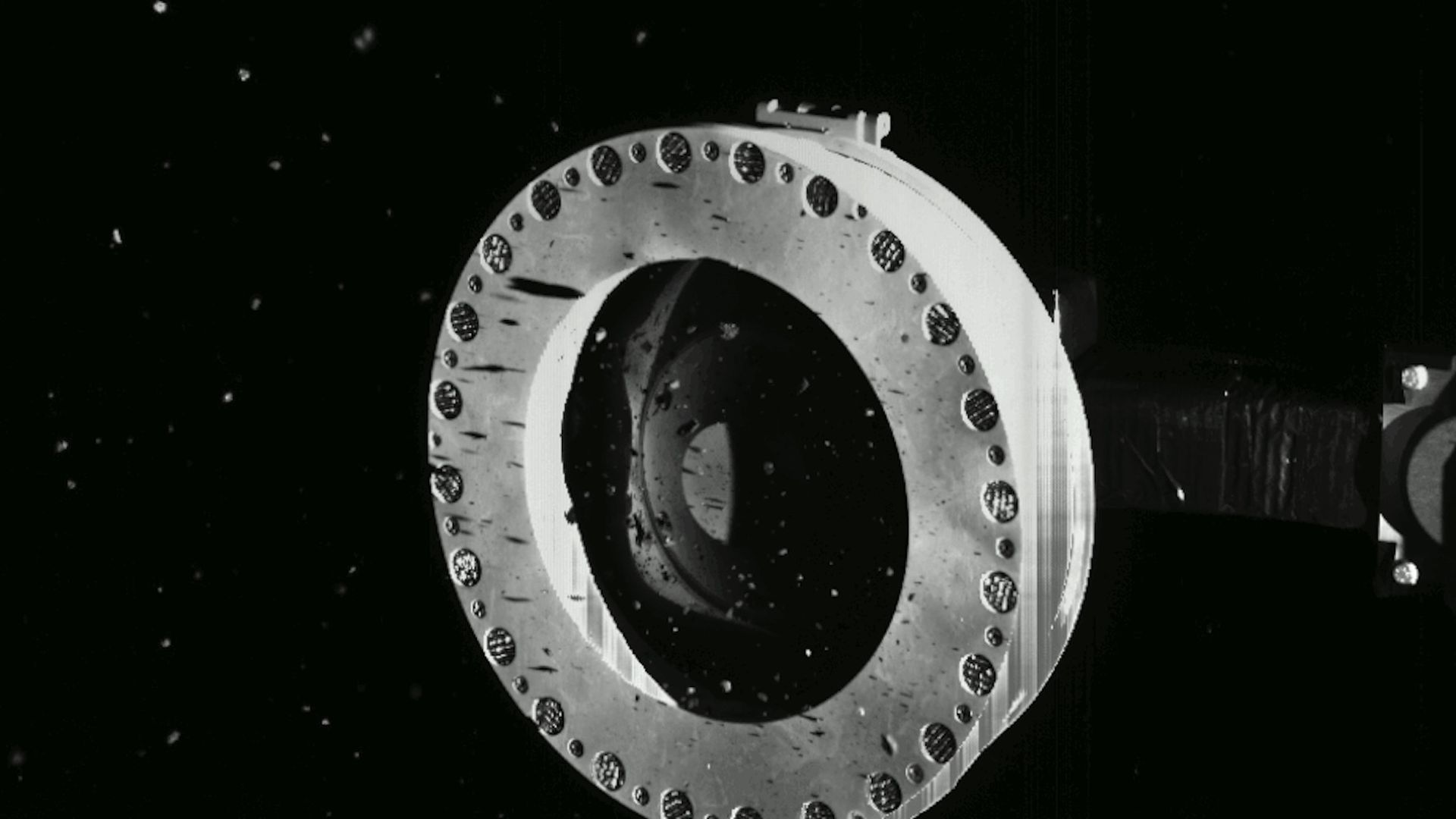 Asteroid bits escaping from the round sampler on OSIRIS-REx