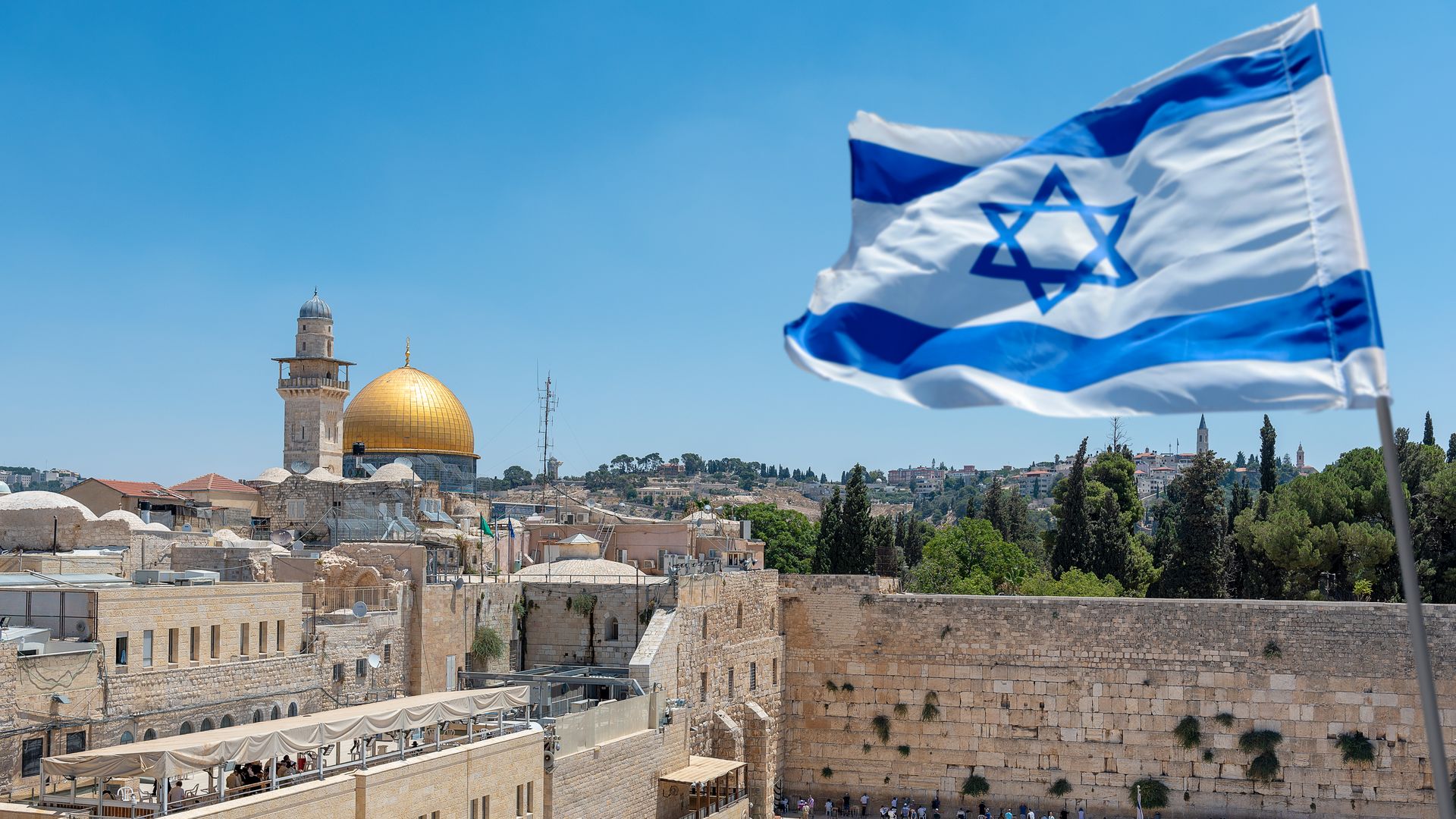 The Wailing Wall and Israeli flag with Al-Aqsa mosque in the background