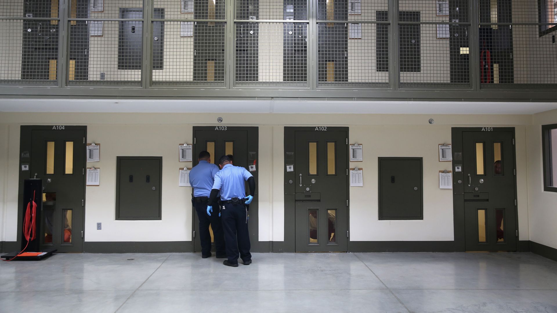 Officers outside of a detention facility cell