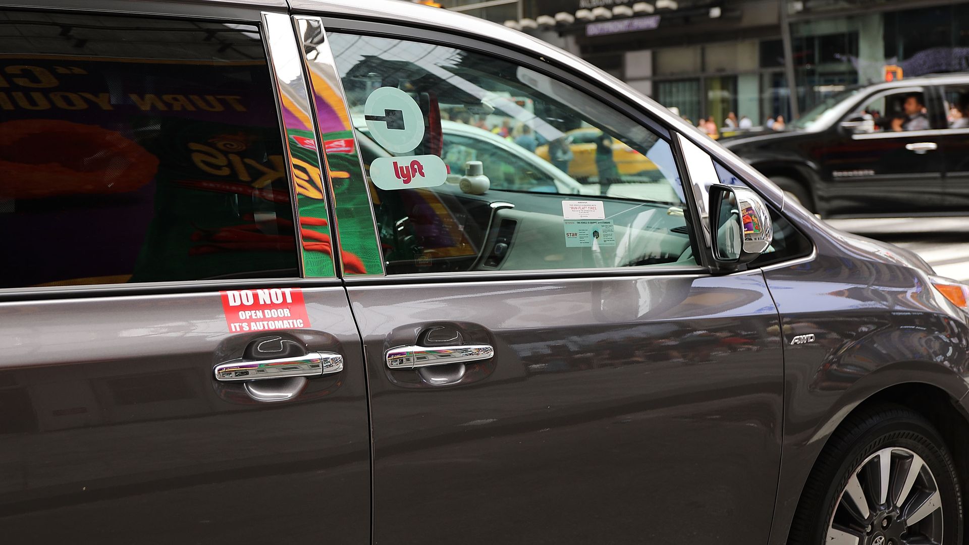 A van with Lyft and Uber window stickers moves through traffic in Manhattan