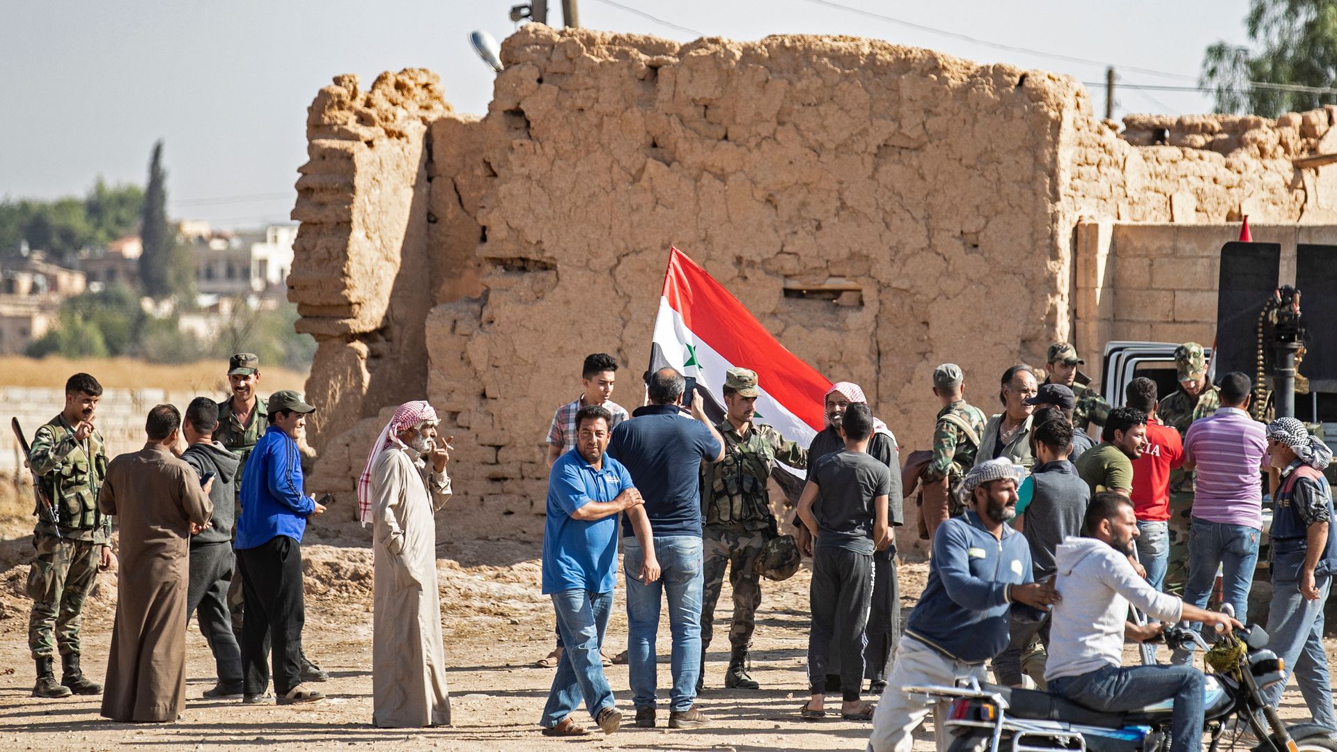 Locals welcome Syrian regime forces as they arrive at the western entrance of the town of Tal Tamr in the countryside of Syria's northeastern Hasakeh province on October 14