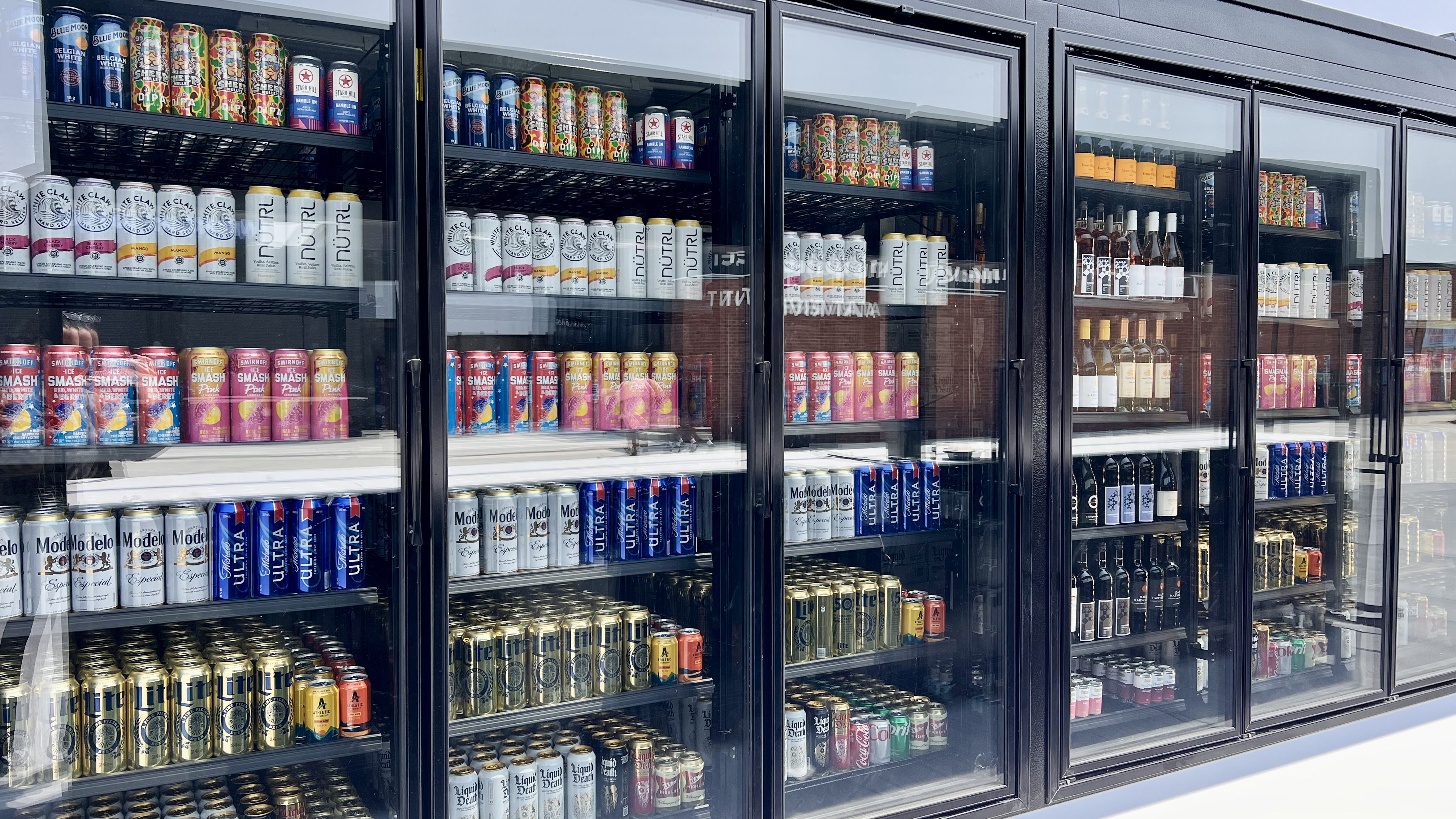 a row of alcohol offerings behind glass