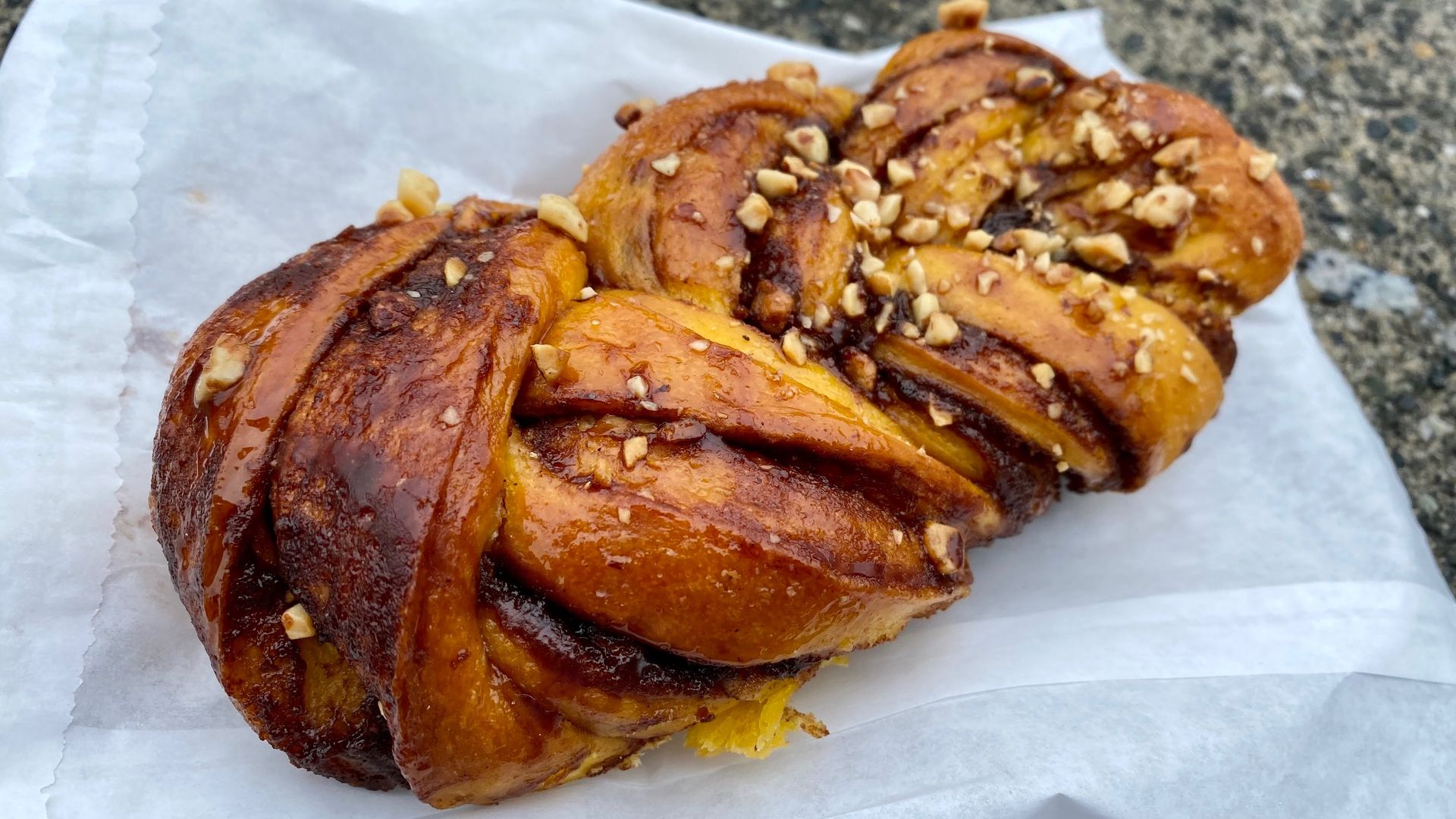 A braided baked pastry with nuts on top and chocolate and cinnamon woven throughout.