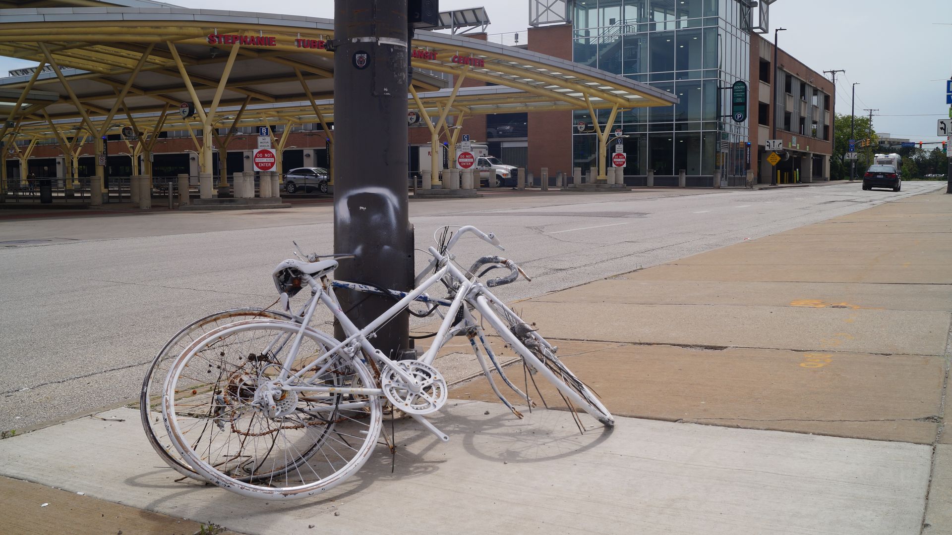 A painted white bicycle leaning up against brown pole