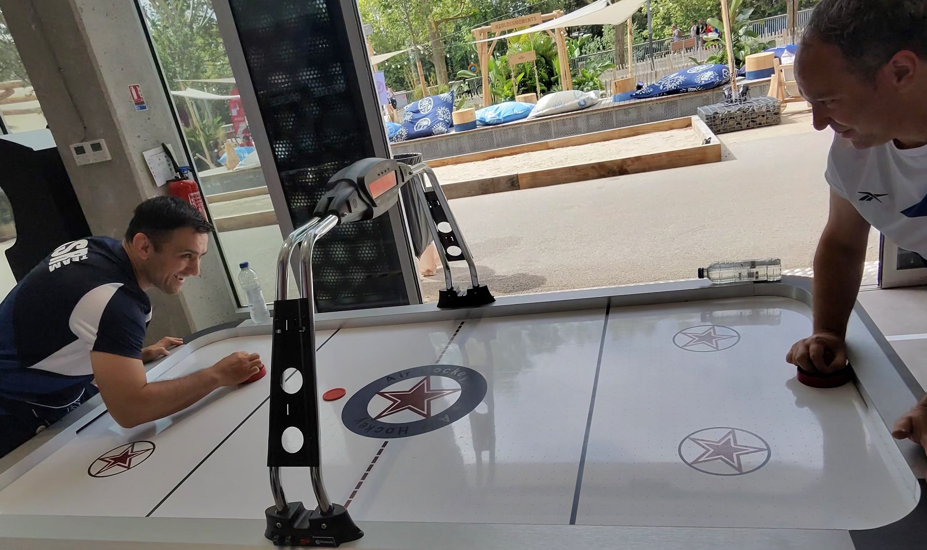 Two Israeli Judo athletes play a game of air hockey at the lounge inside the Olympic Village.