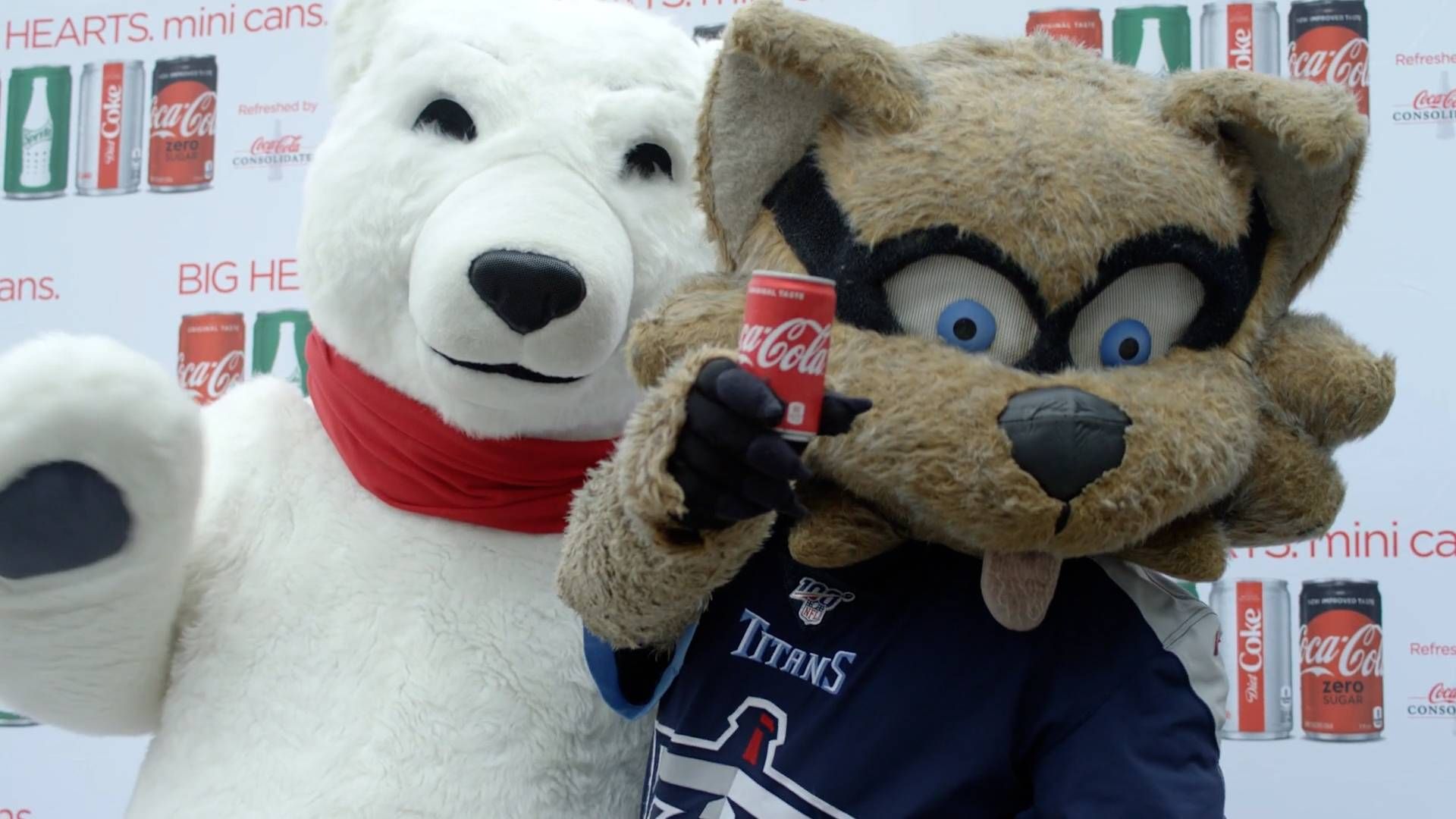 The Coca-Cola polar bear mascot and the Tennessee Titans mascot pose together, with the Titans mascot holding a mini can of Coca-Cola.