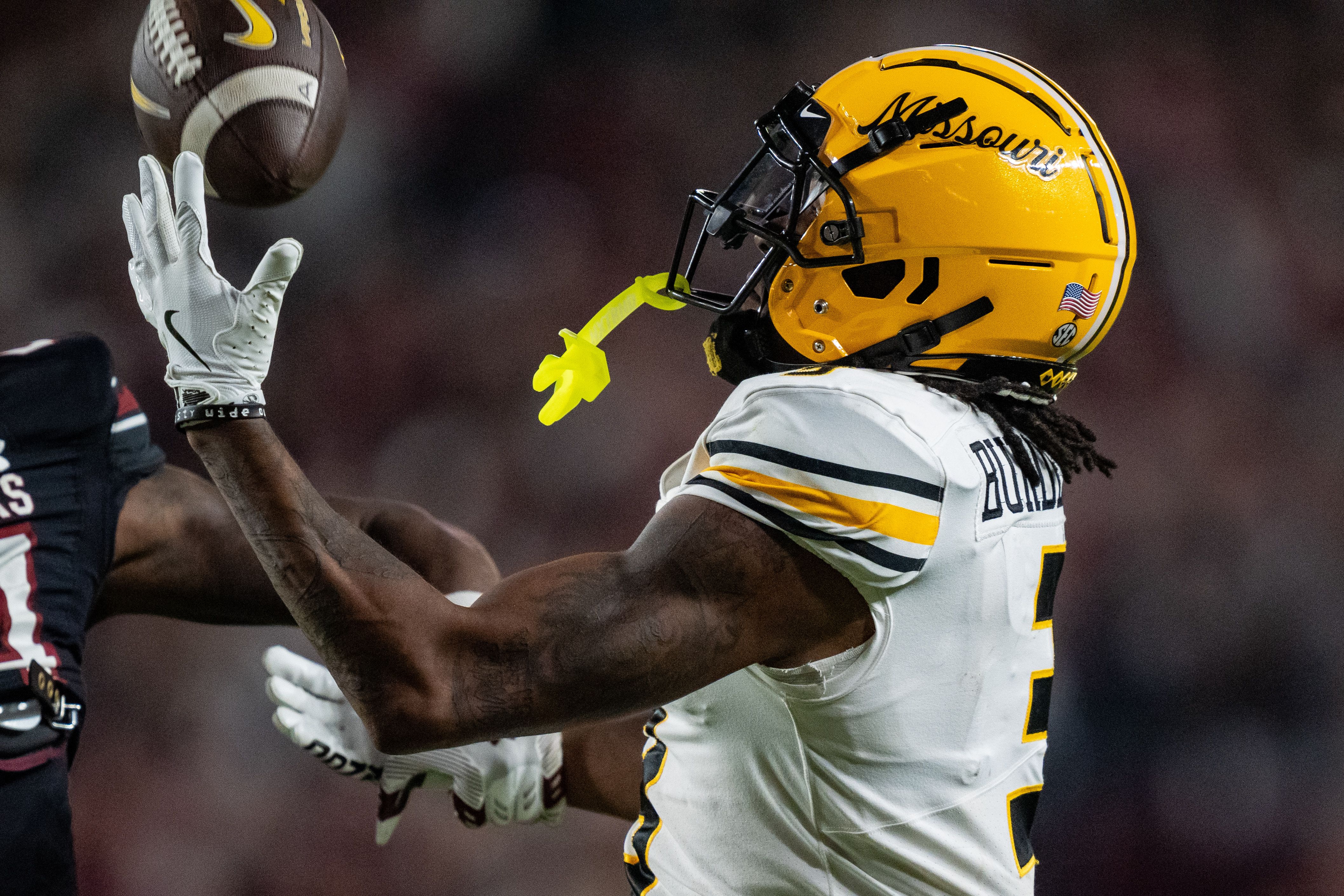 Photo of a football player catching a pass in a game on a field. 